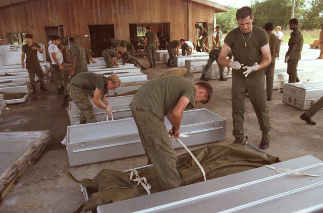 <p>Military personnel place bodies in coffins at the airport in Georgetown, Guyana</p>