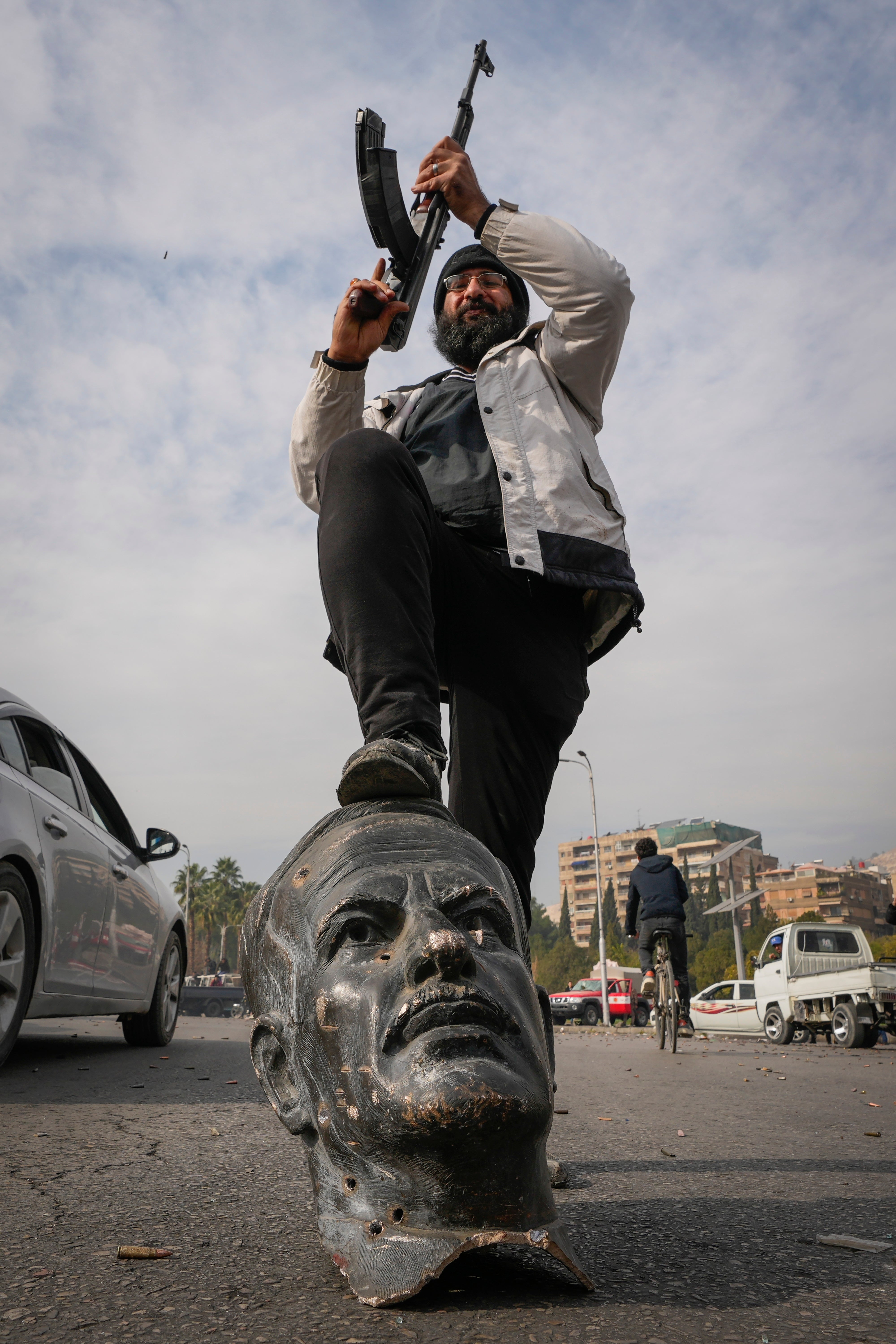 An opposition fighter steps on a broken bust of the late Syrian president Hafez Assad in Damascus