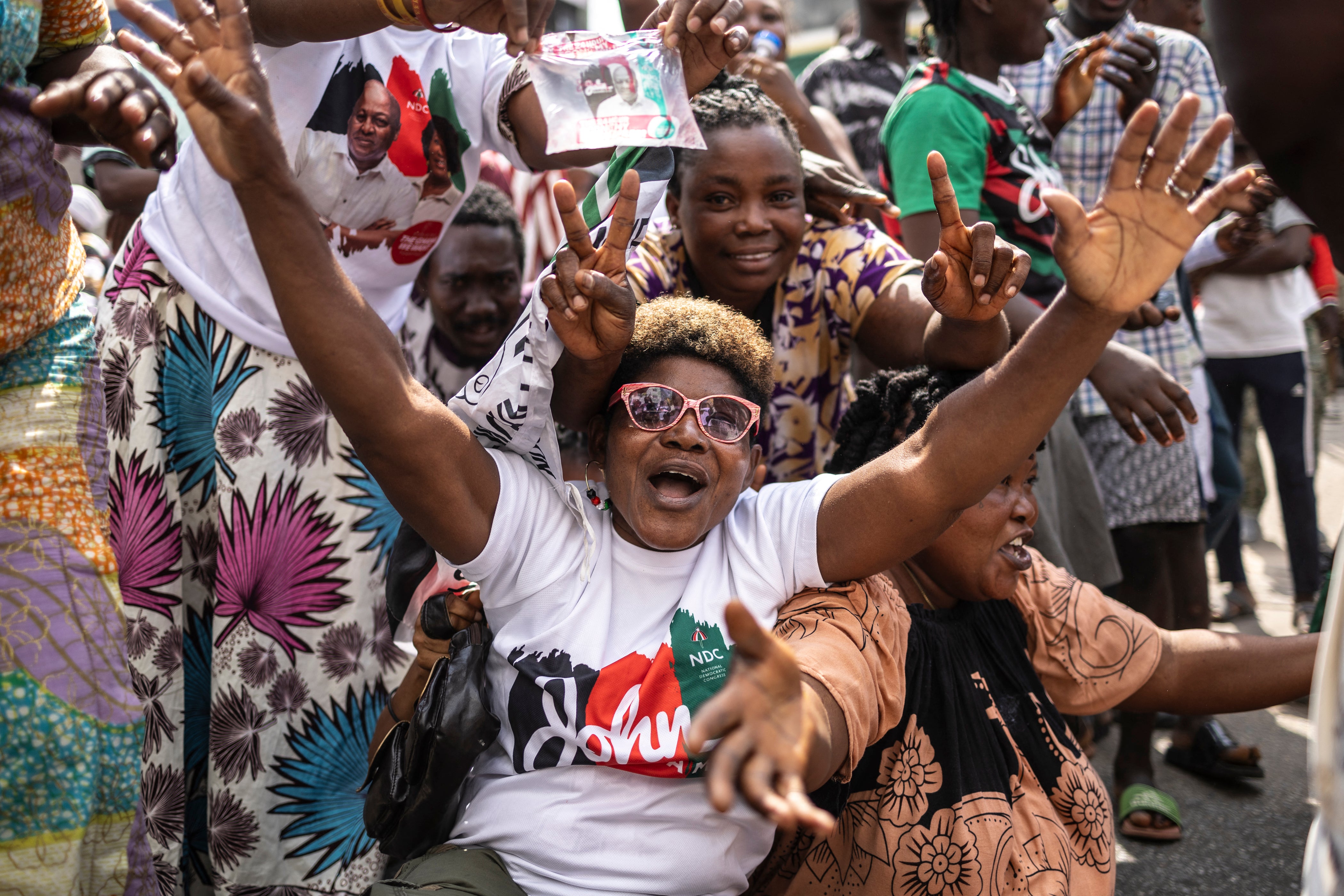 A supporter of former Ghana president and presidential candidate of the National Democratic Congress (NDC) party John Mahama wearing a t-shirt with the party's colours gestures