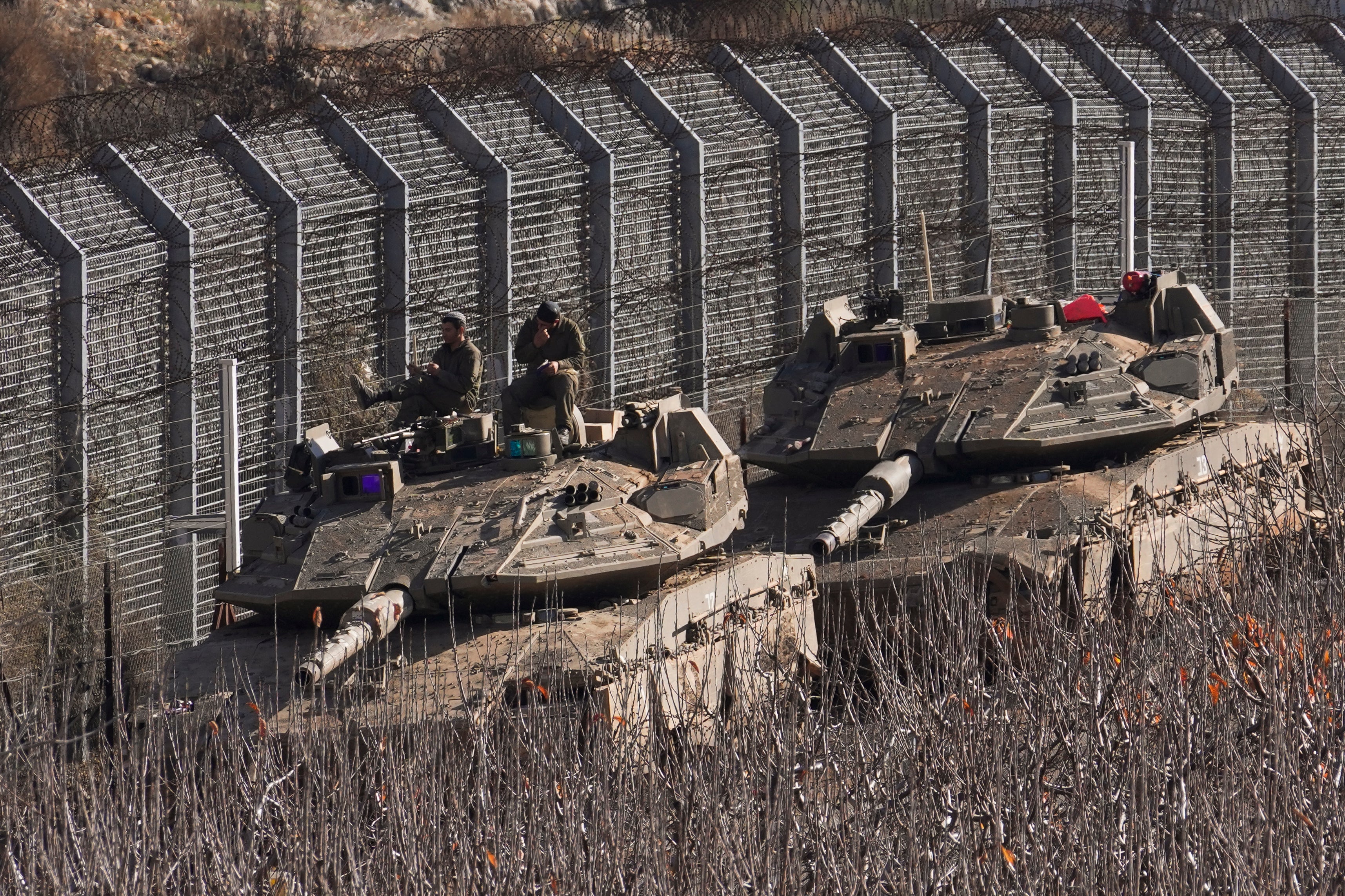 Israeli soldiers sit on top of a tank along the so-called Alpha Line that separates the Israeli-annexed Golan Heights from Syria proper