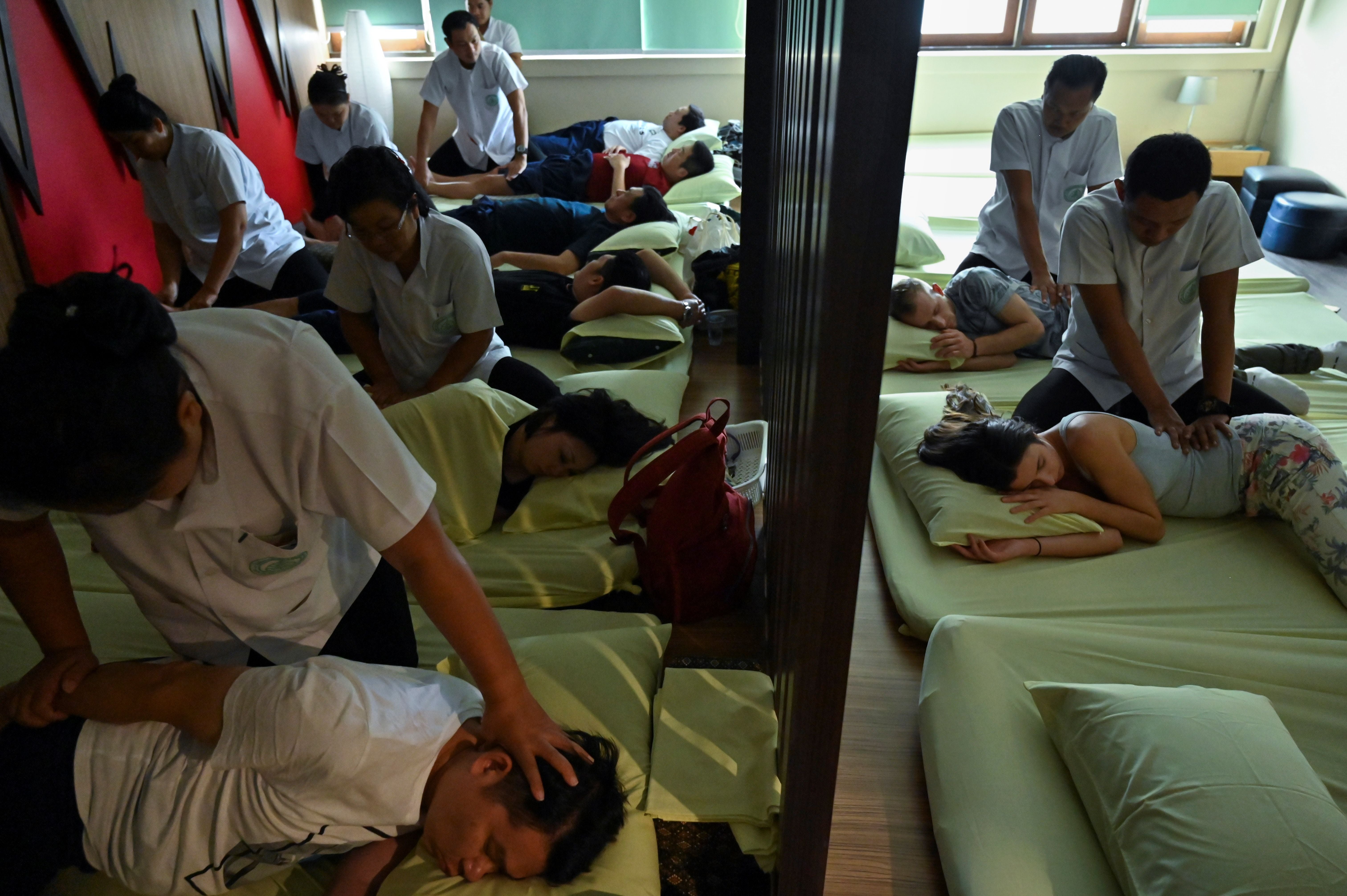 File. Tourists are massaged at Wat Po Thai centre outside the Wat Po temple in Bangkok