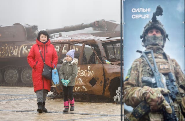 <p>A woman and a child walk past destroyed Russian military machinery near St. Mykhailivsky Cathedral in Kyiv</p>