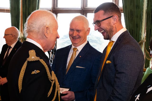 King Charles presents an Elizabeth Emblem to Bryndon Hughes (centre), for Pc Nicola Hughes during the inaugural presentation ceremony at Windsor Castle (Aaron Chown/PA)