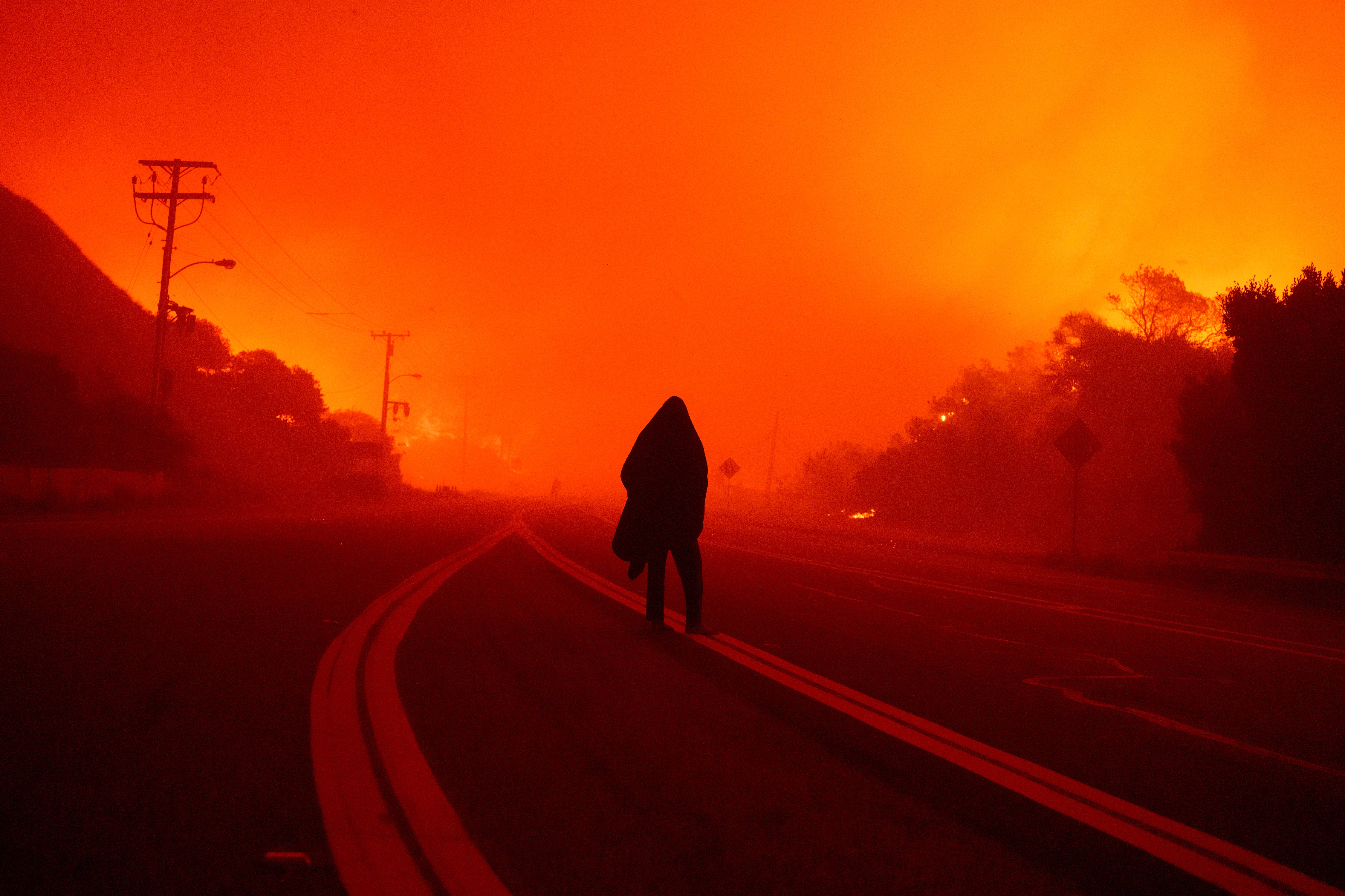 A person walks along Malibu Canyon road on Tuesday as the Franklin Fire approaches in Malibu, California. The fire was moving south on Tuesday morning