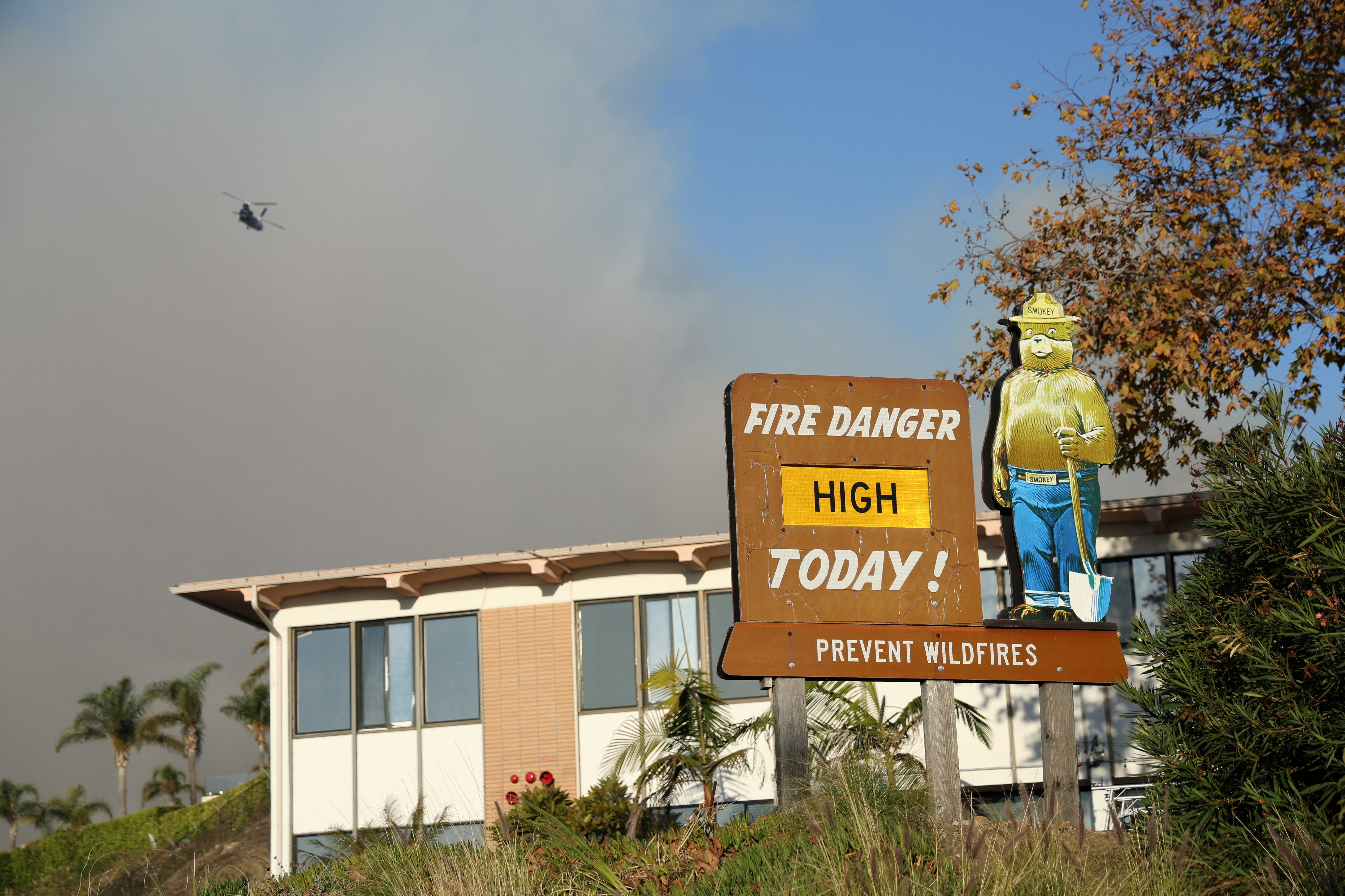 A fire danger sign stands amid smoke from Tuesday’s Franklin Fire in Malibu, California. Winds were expected to pick up again at night