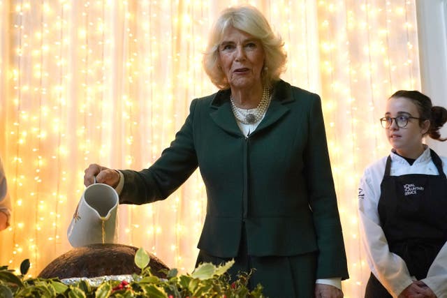 Camilla poured brandy over a Christmas pudding at an RVS lunch (Alberto Pezzali/PA)