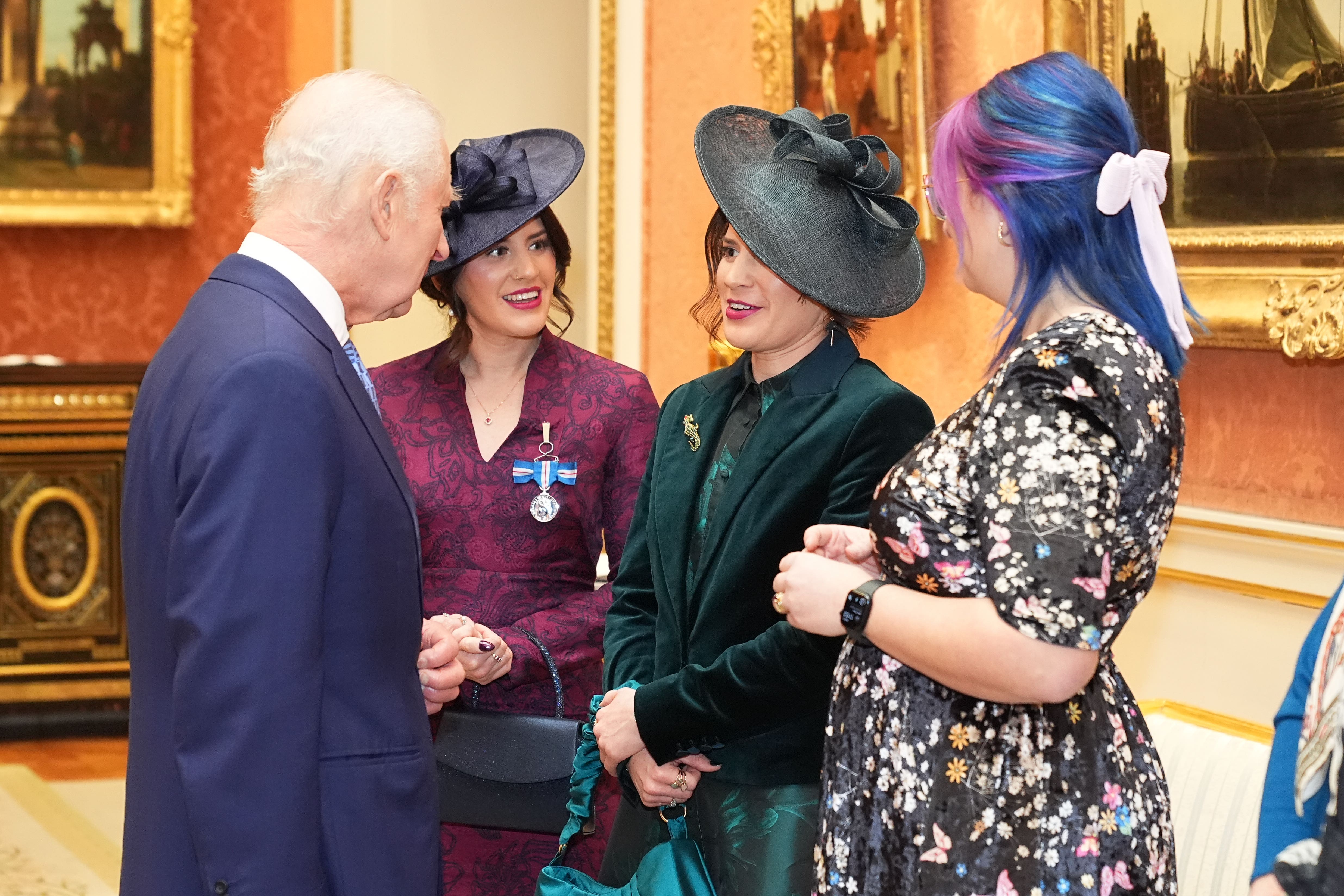 Georgia Laurie (second right), is decorated with the King’s Gallantry Medal by the King and joined by her sister Melissa (centre) (Aaron Chown/PA)