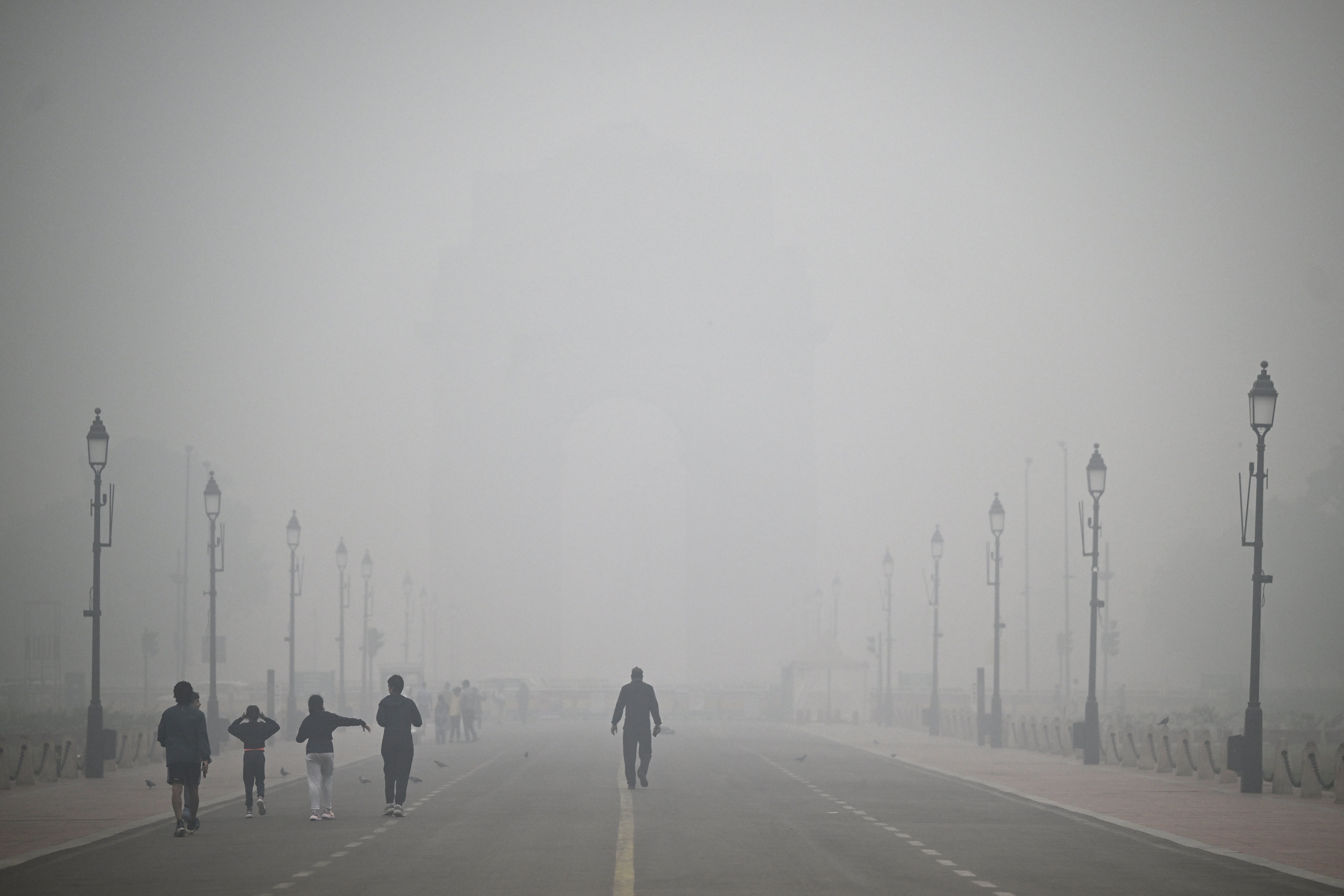 Pedestrians walk along the Kartavya Path engulfed in thick smog near India Gate in New Delhi on 18 November 2024