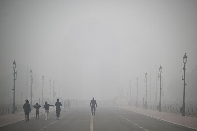 <p>Pedestrians walk amid thick smog near India Gate in New Delhi on 18 November 2024</p>