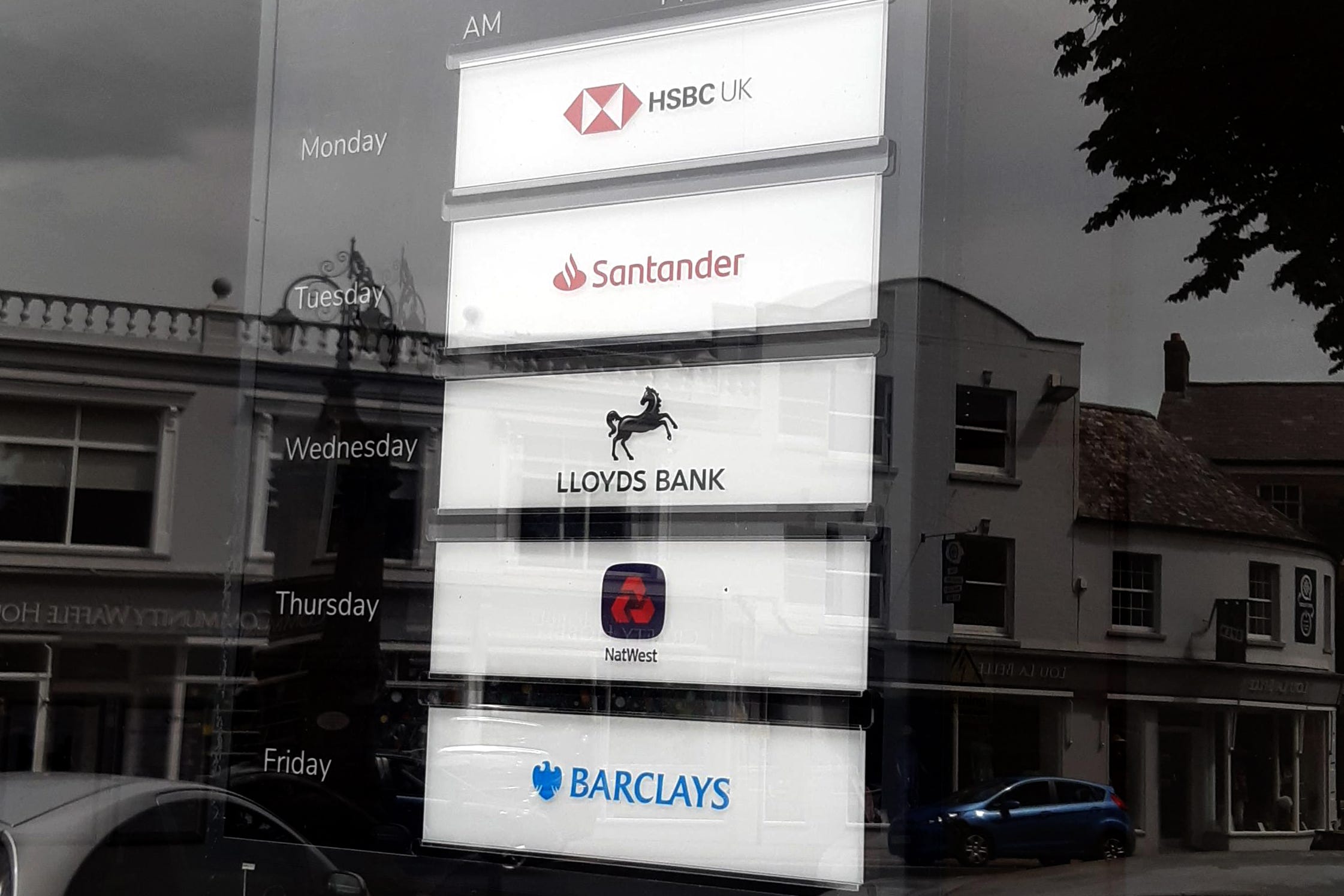 A sign in a banking hub window in Axminster, Devon, displaying the days that bank representatives are available to help customers