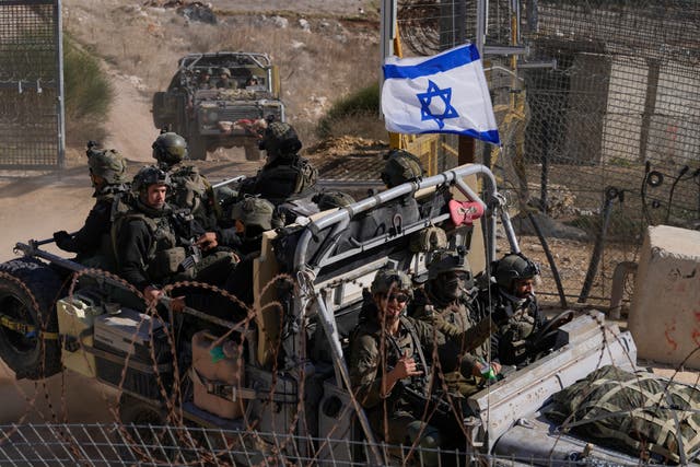 <p>Israeli soldiers cross the security fence near the Alpha Line separating occupied Golan Heights from the rest of Syria</p>