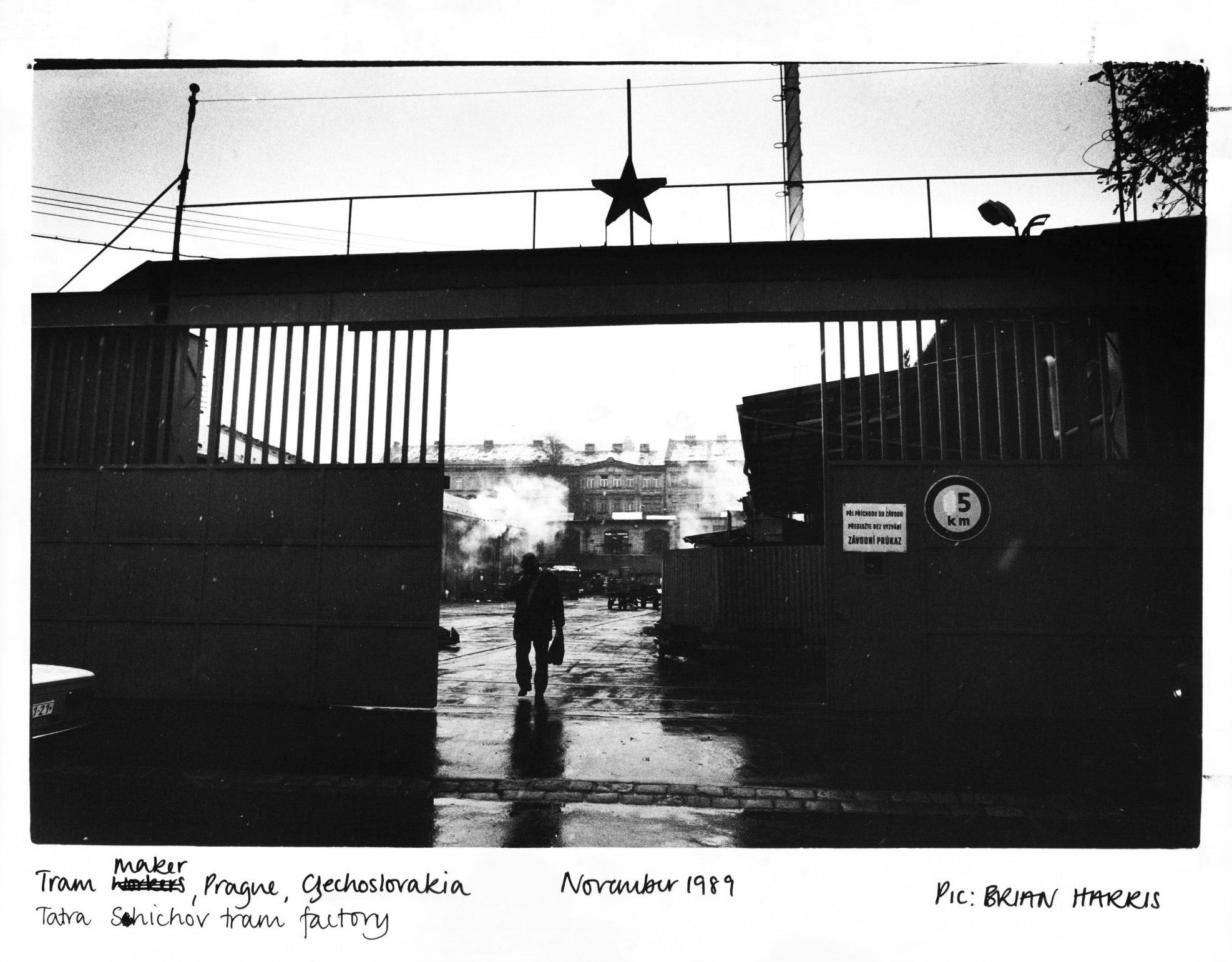 A tram maker leaving a factory in Prague. A Communist star looms large above the gates