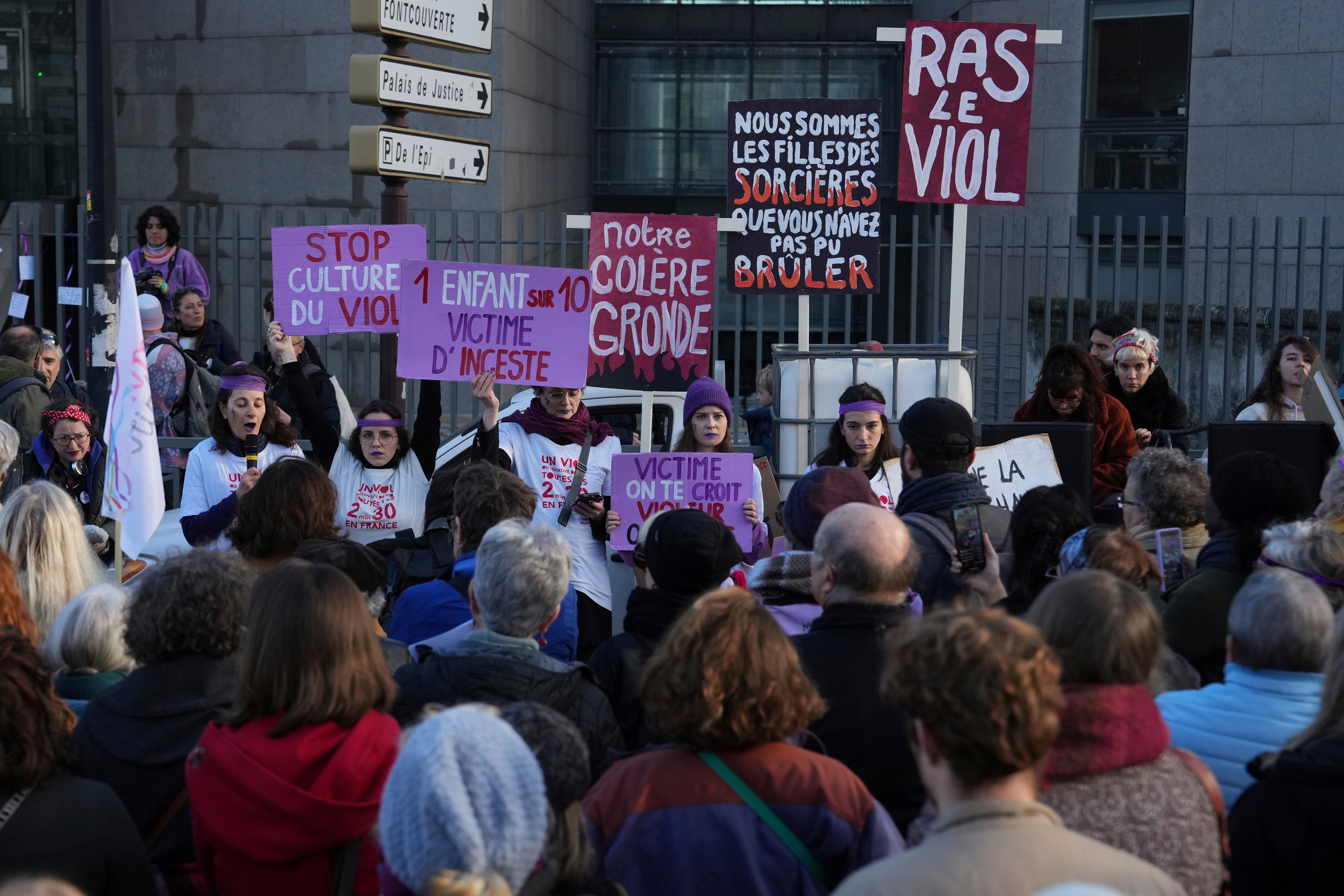 Activists hold posters in front of the Palace of Justice during a women's rights demonstration, Saturday, Dec. 14, 2024 in Avignon, southern France, where the trial of dozens of men accused of raping Gisèle Pelicot while she was drugged and rendered unconscious by her husband took place