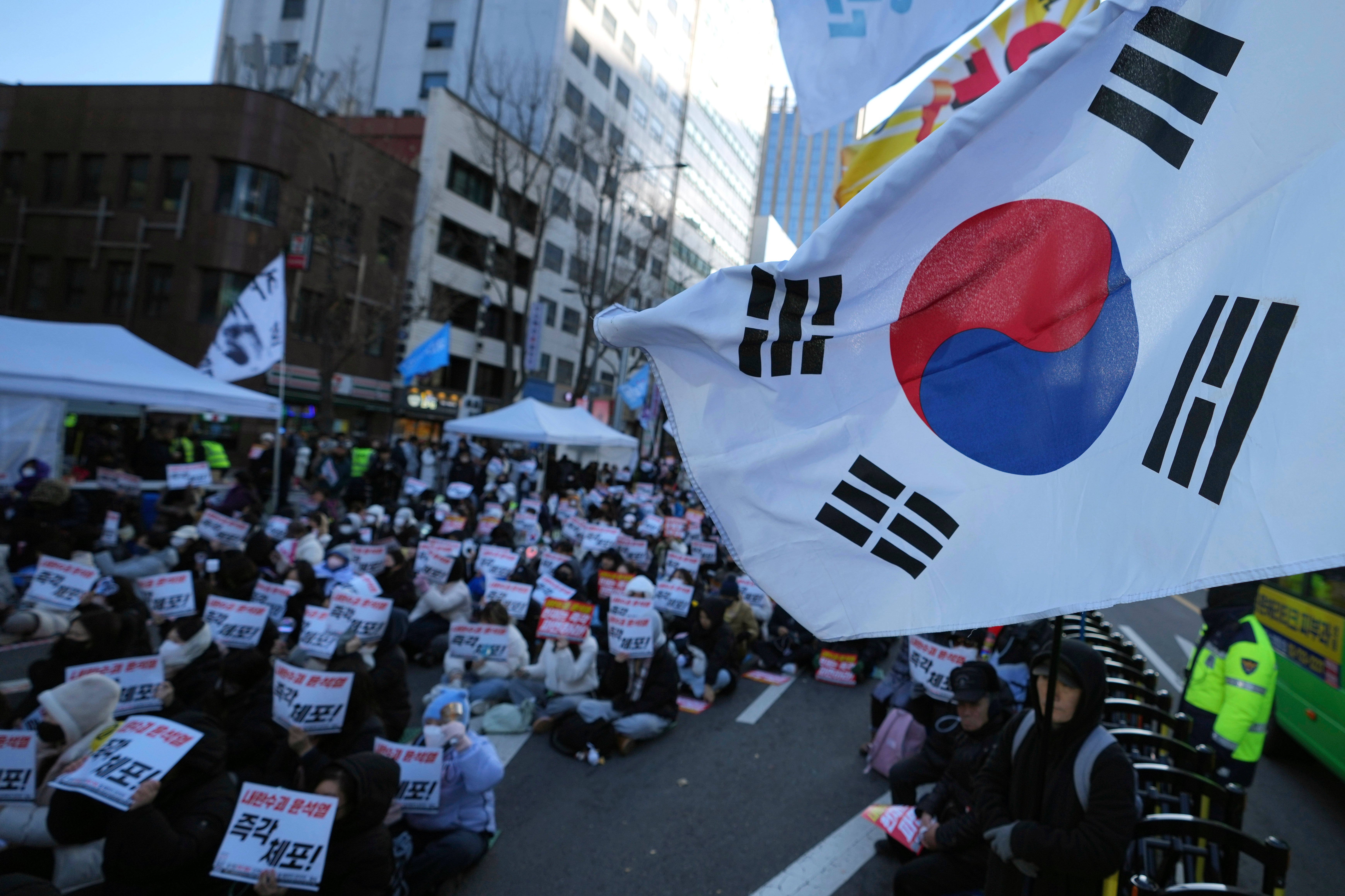 Participants hold signs during a rally calling on the Constitutional Court to dismiss president Yoon Suk Yeol in Seoul on 15 December 2024. The signs read ‘Immediately arrest’