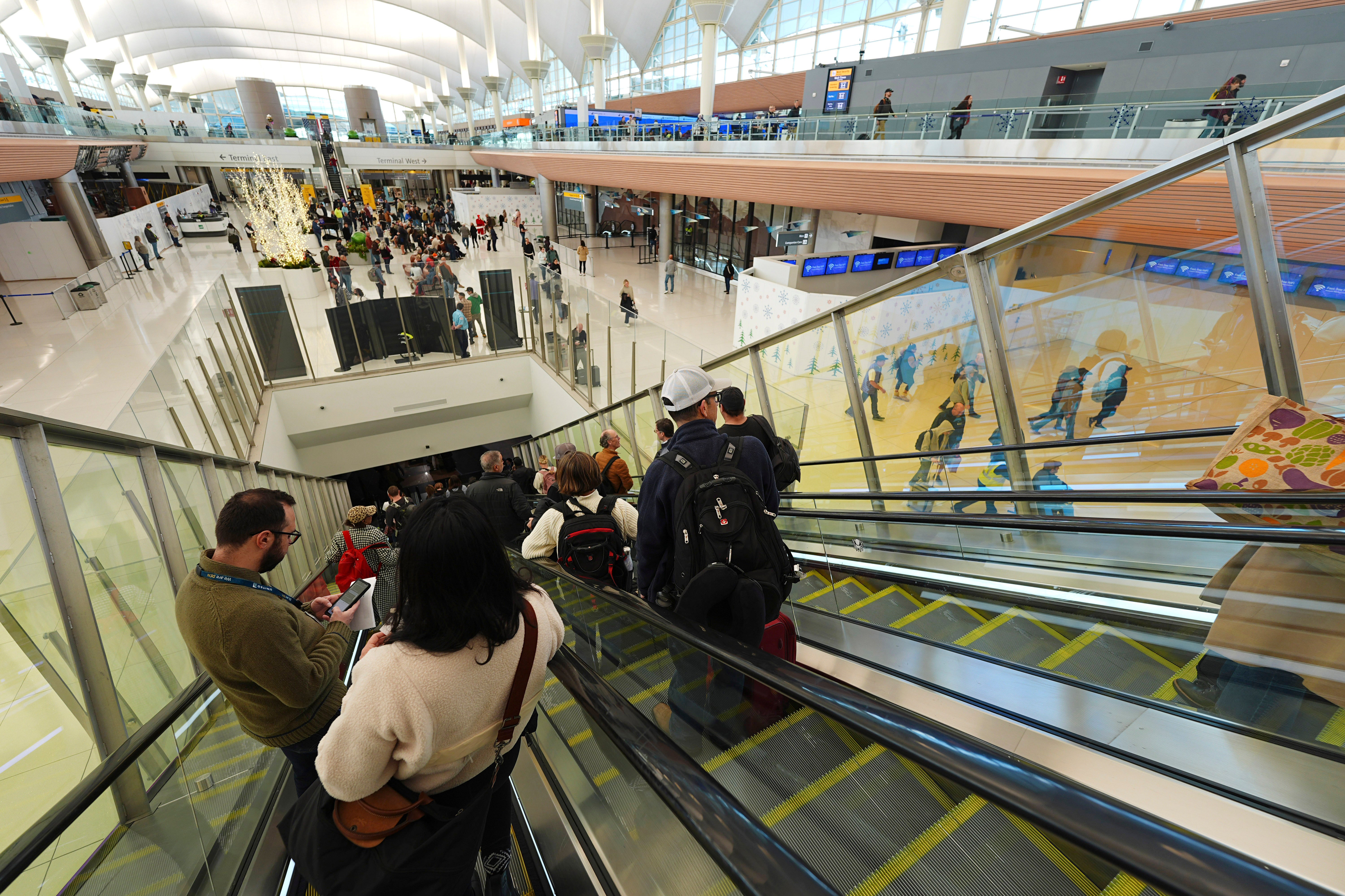 Travelers move down escalators in Colorado’s Denver International Airport on Saturday. Nearly 120 million Americans are expected to travel for the holidays this month