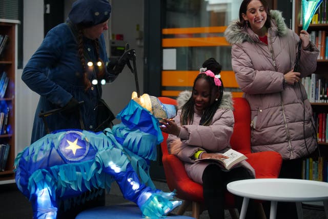 <p>Fundraiser Alex McCormick (right) watching Pearl Ogunyadeka, 10, reading a book inside Spellow Community Hub and Library in Walton, Liverpool, ahead of its reopening after it was torched during riots on County Road in Augus</p>