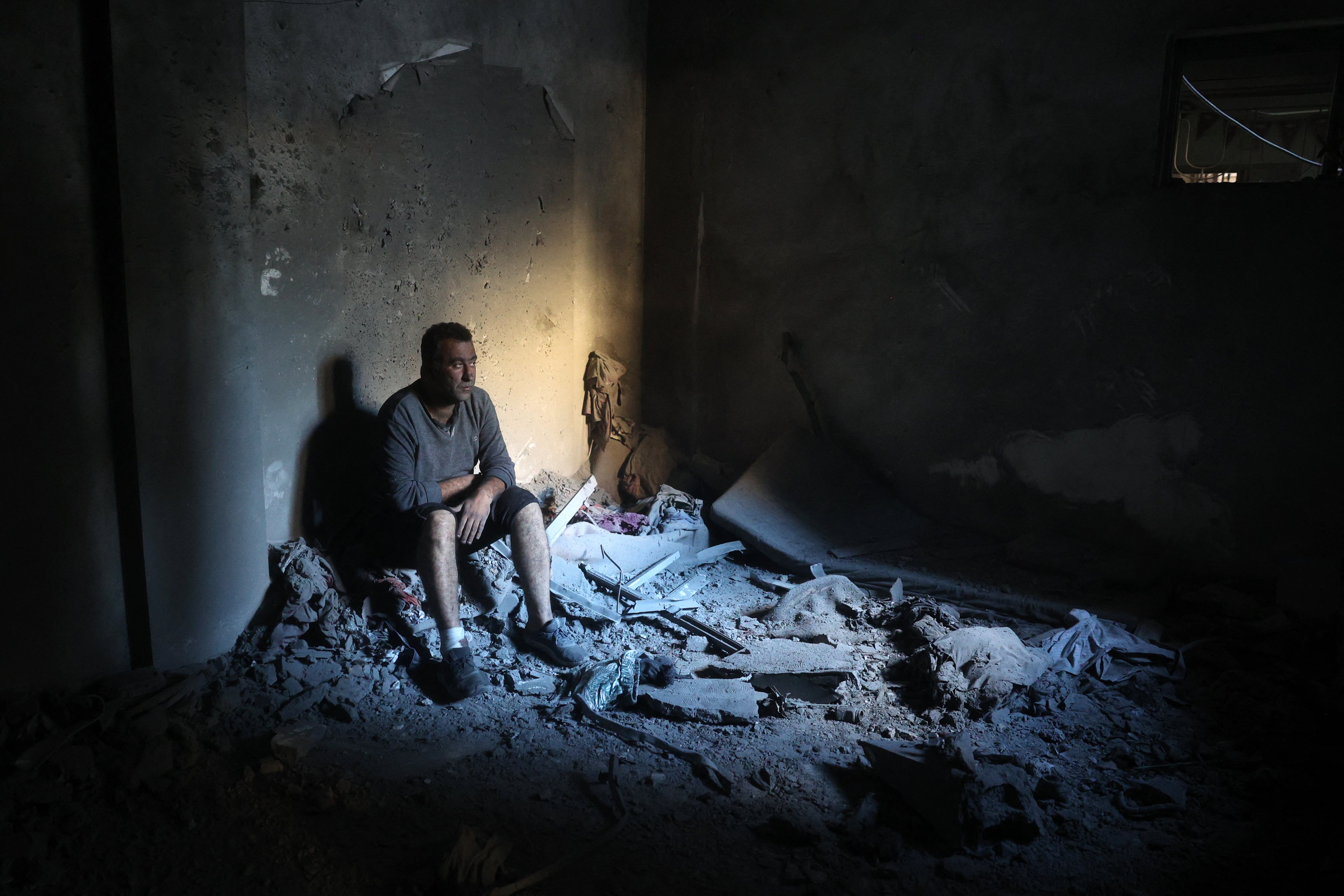 A Palestinian man sits inside a destroyed building in the Nuseirat refugee in the central Gaza Strip on December 13