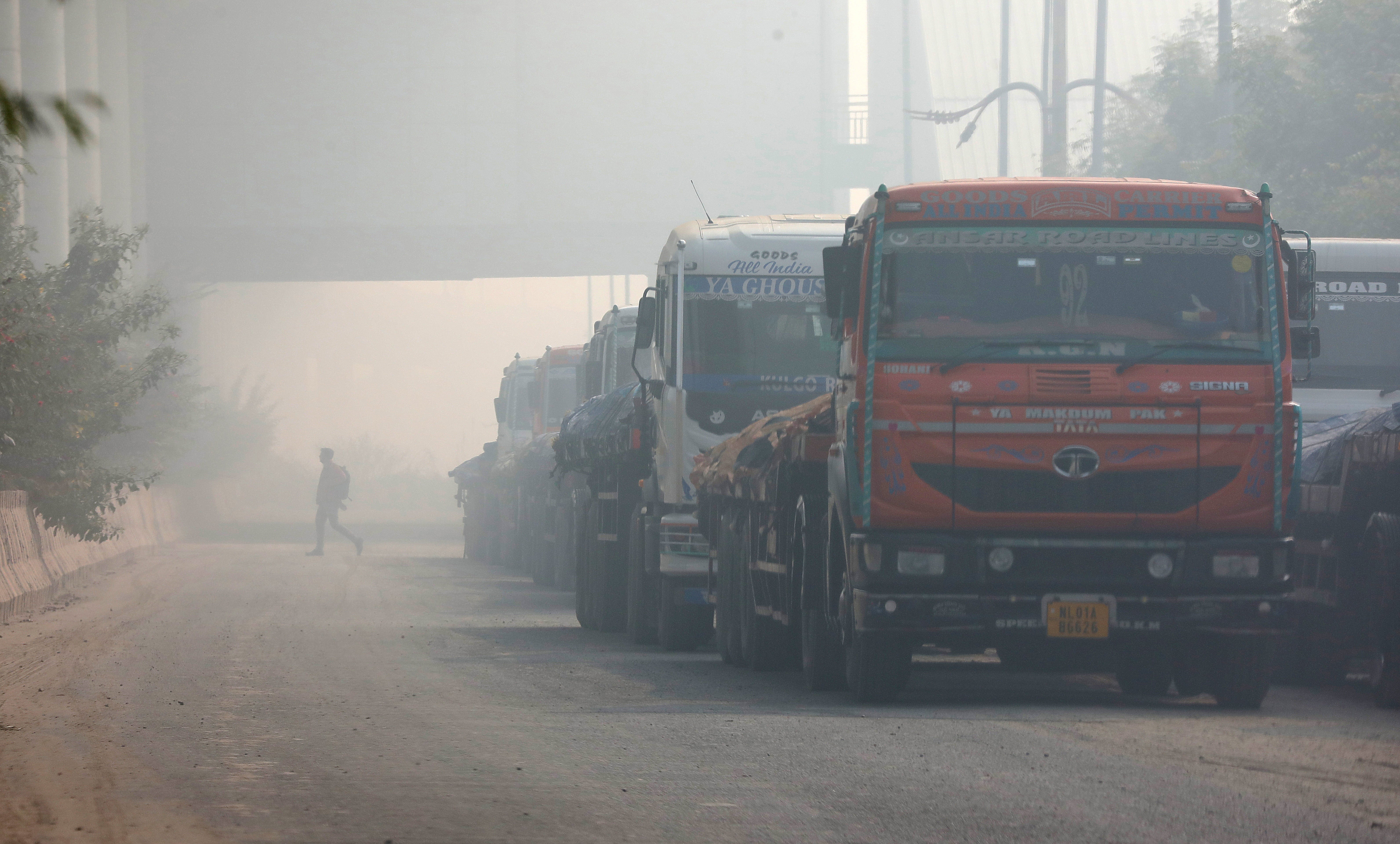 Trucks parked at a construction site amid the heavy smog near New Delhi, India, 17 December 2024