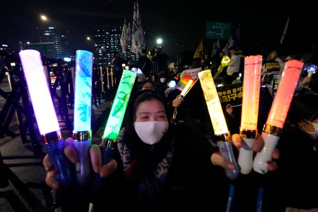 <p>A woman waves light sticks during a rally demanding the arrest of impeached South Korean President Yoon Suk Yeol in Seoul, South Korea, Monday</p>