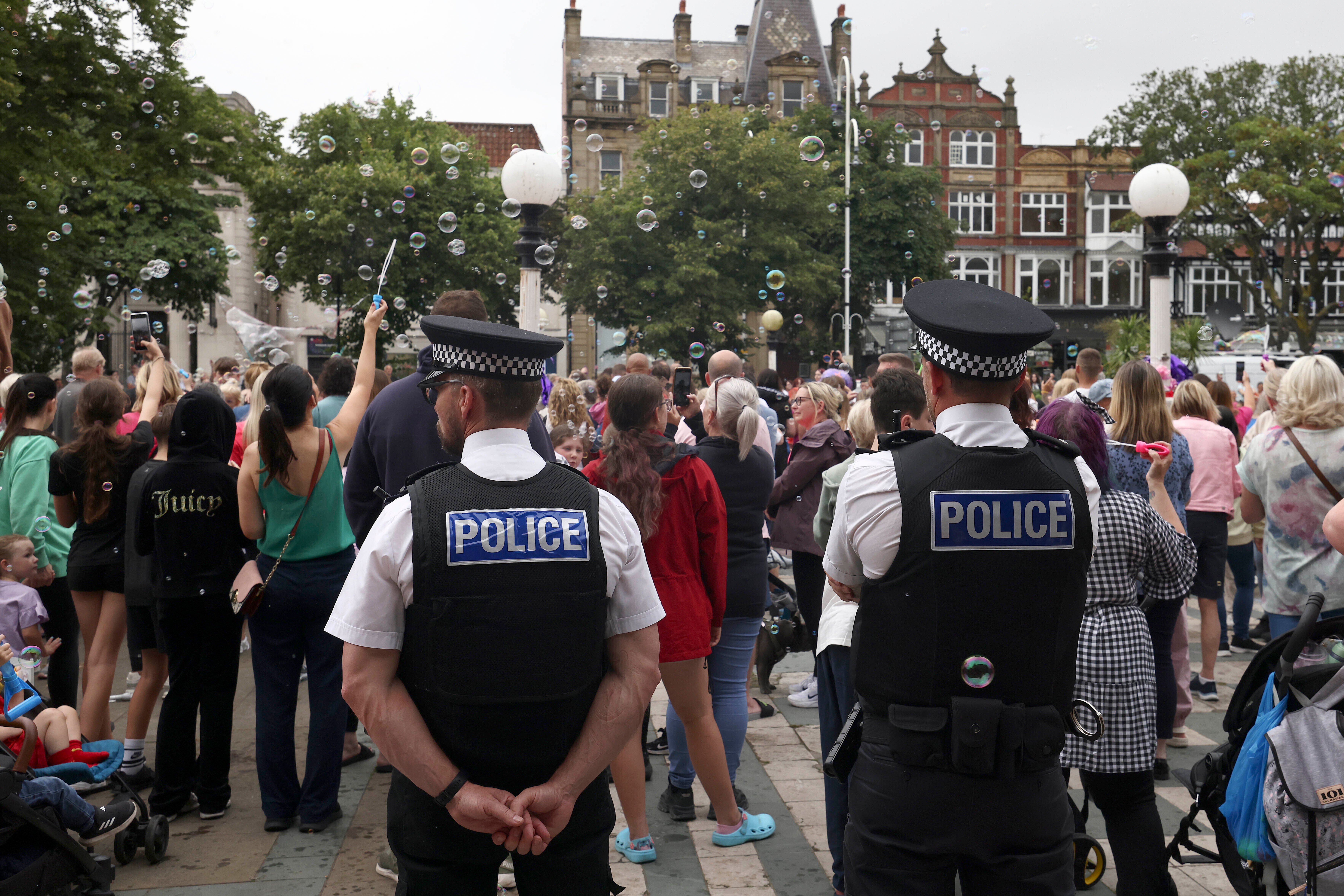 File. Police officers watch members of the public outside the Town Hall in Southport on 5 August 2024 after three young girls were killed in a knife attack at a holiday club the week before