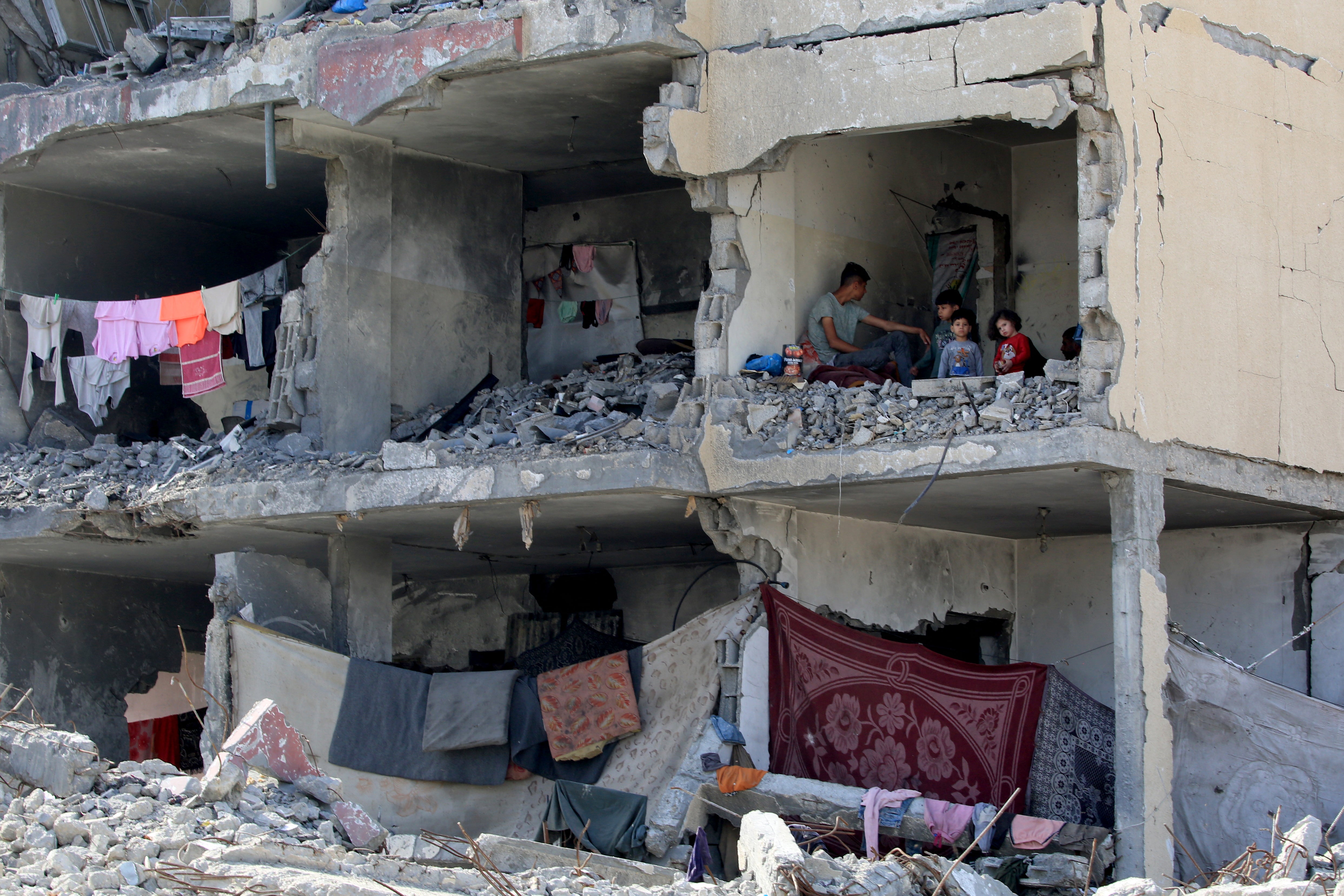 A Palestinian man and his children sit in a destroyed room following the targeting or a residential building by an Israeli airstrike in Rafah in the southern Gaza Strip on May 22, 2024, amid the ongoing conflict between Israel and the Palestinian Hamas group.