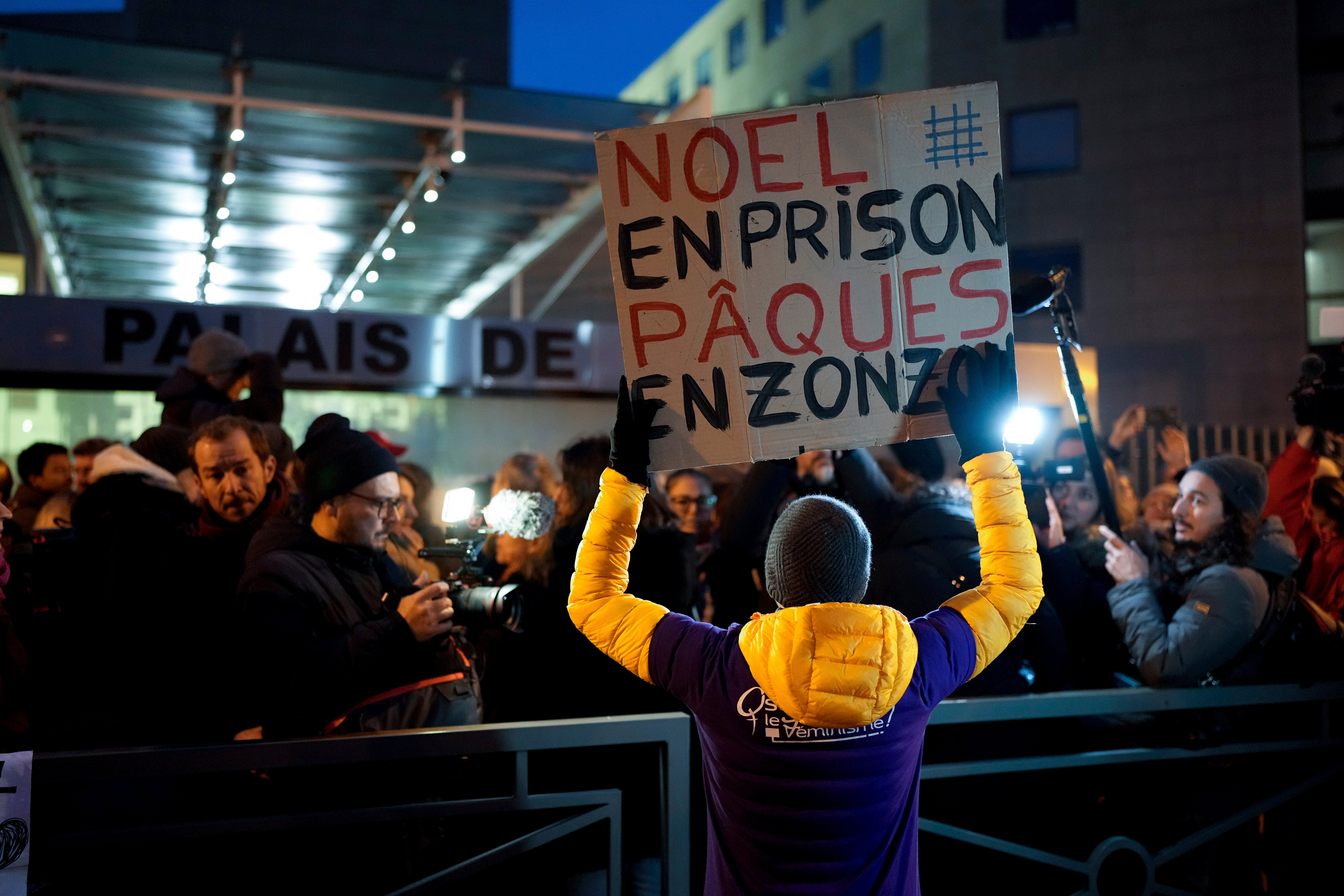 A man with a placard reading "Christmas in prison, Easter in the slammer"