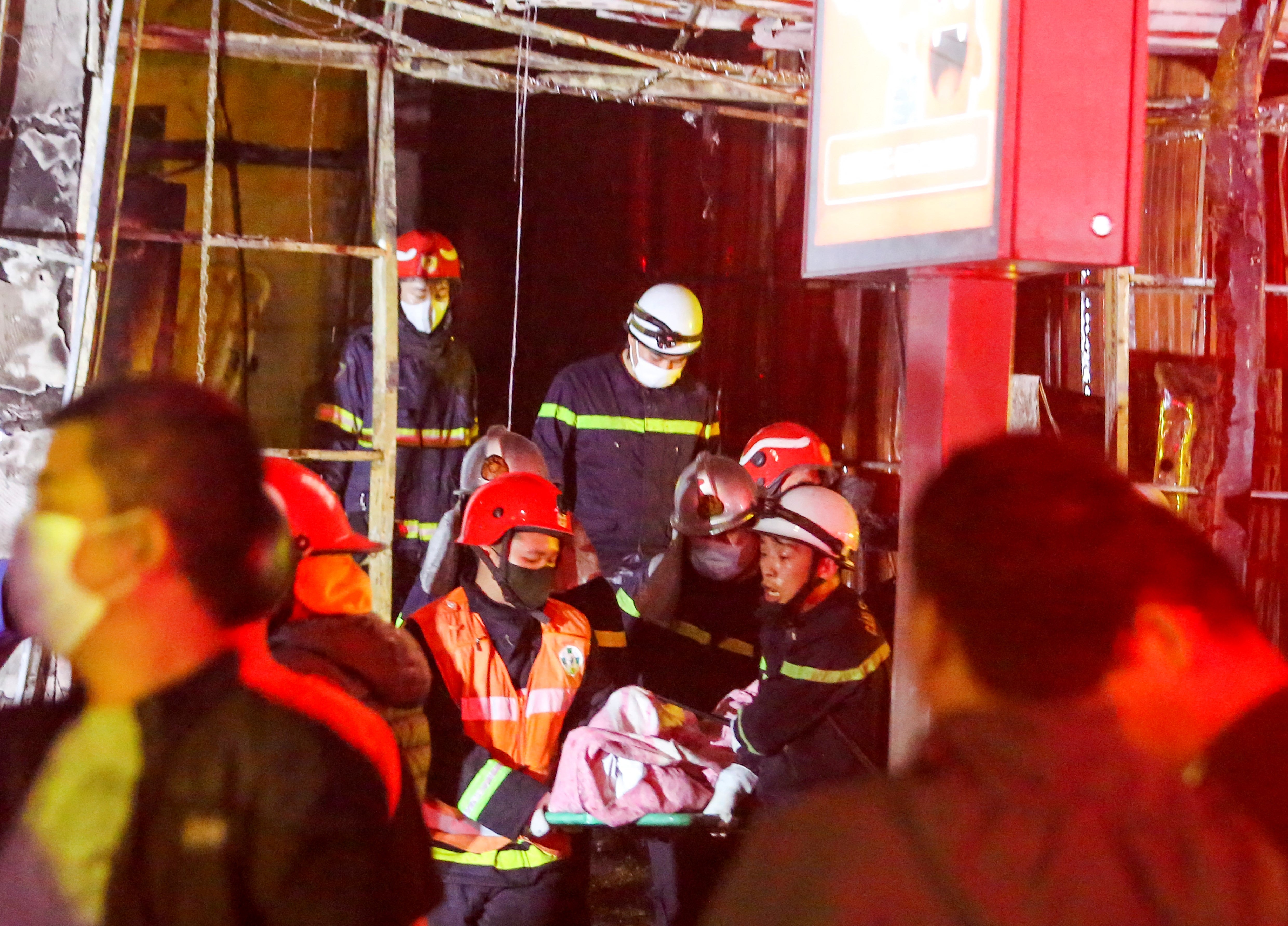 Fire and rescue workers carry a victim to an ambulance following a fire at a karaoke bar in Hanoi