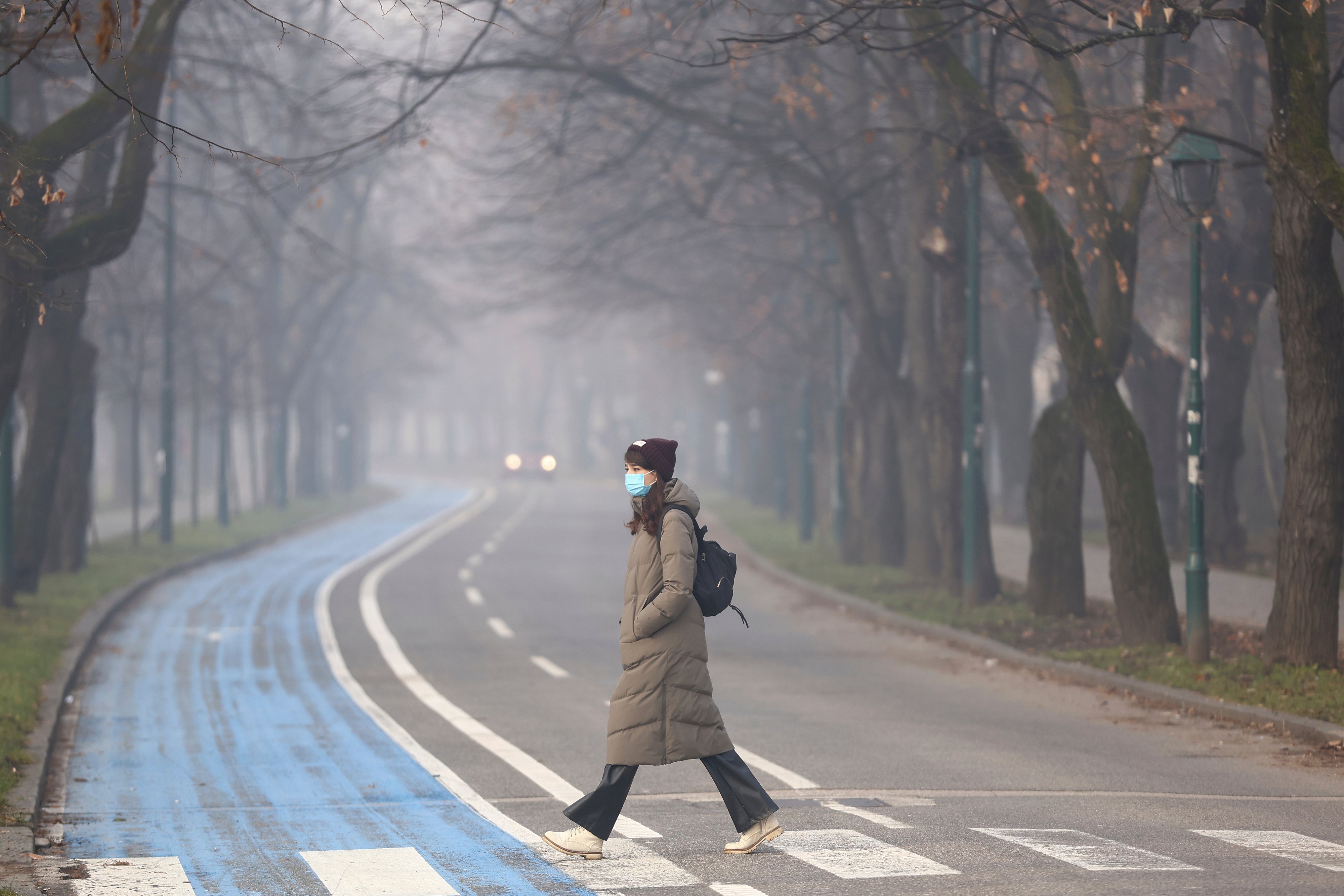 A woman wears a face mask shrouded by pollution haze as smog covers Sarajevo, Bosnia, Thursday, Dec. 19, 2024