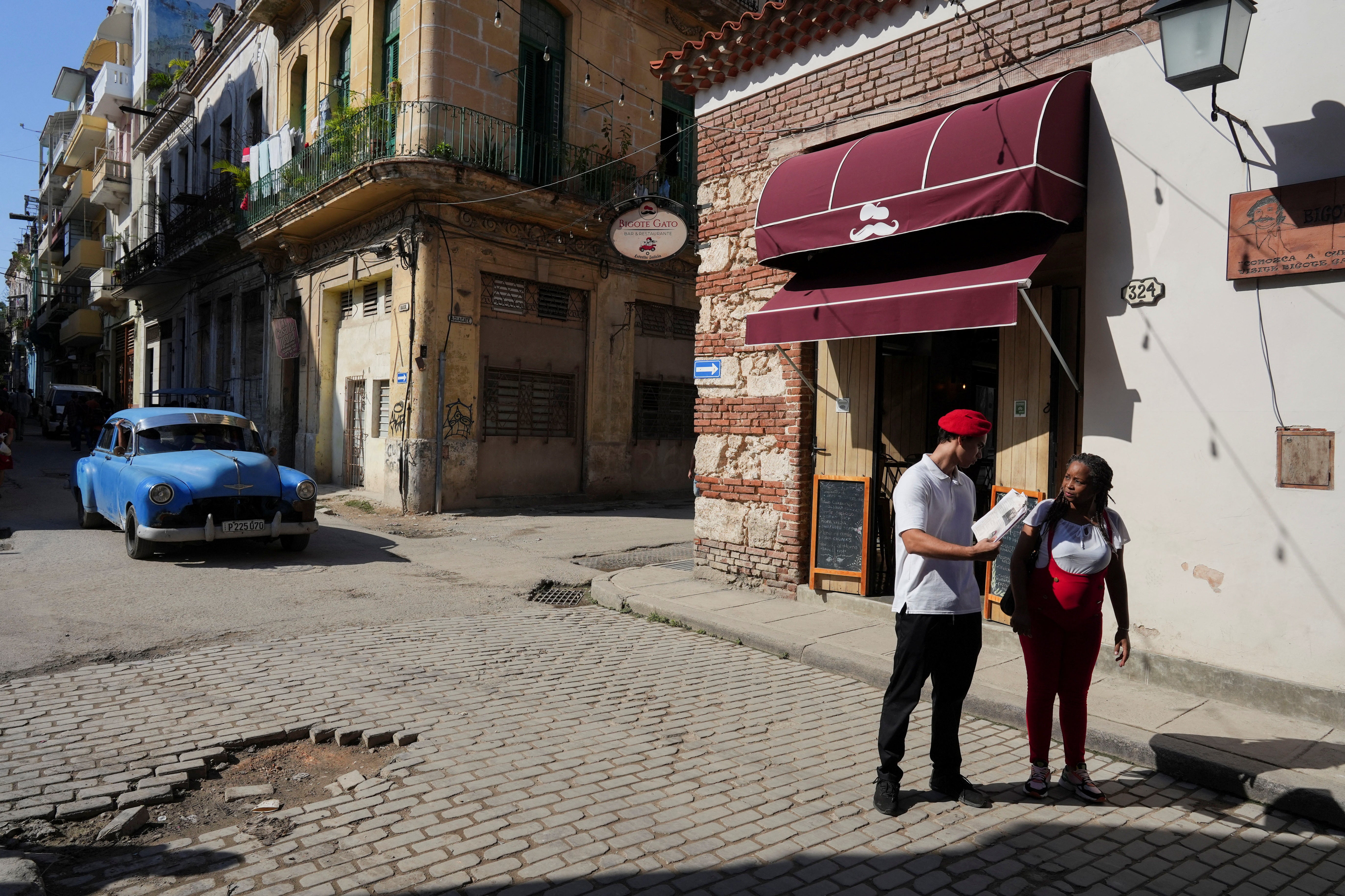 A restaurant employee tries to convince a tourist to enter and have a meal, in downtown Havana