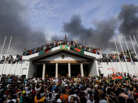 Anti-government protestors display Bangladesh’s national flag as they storm Prime Minister Sheikh Hasina’s palace in Dhaka