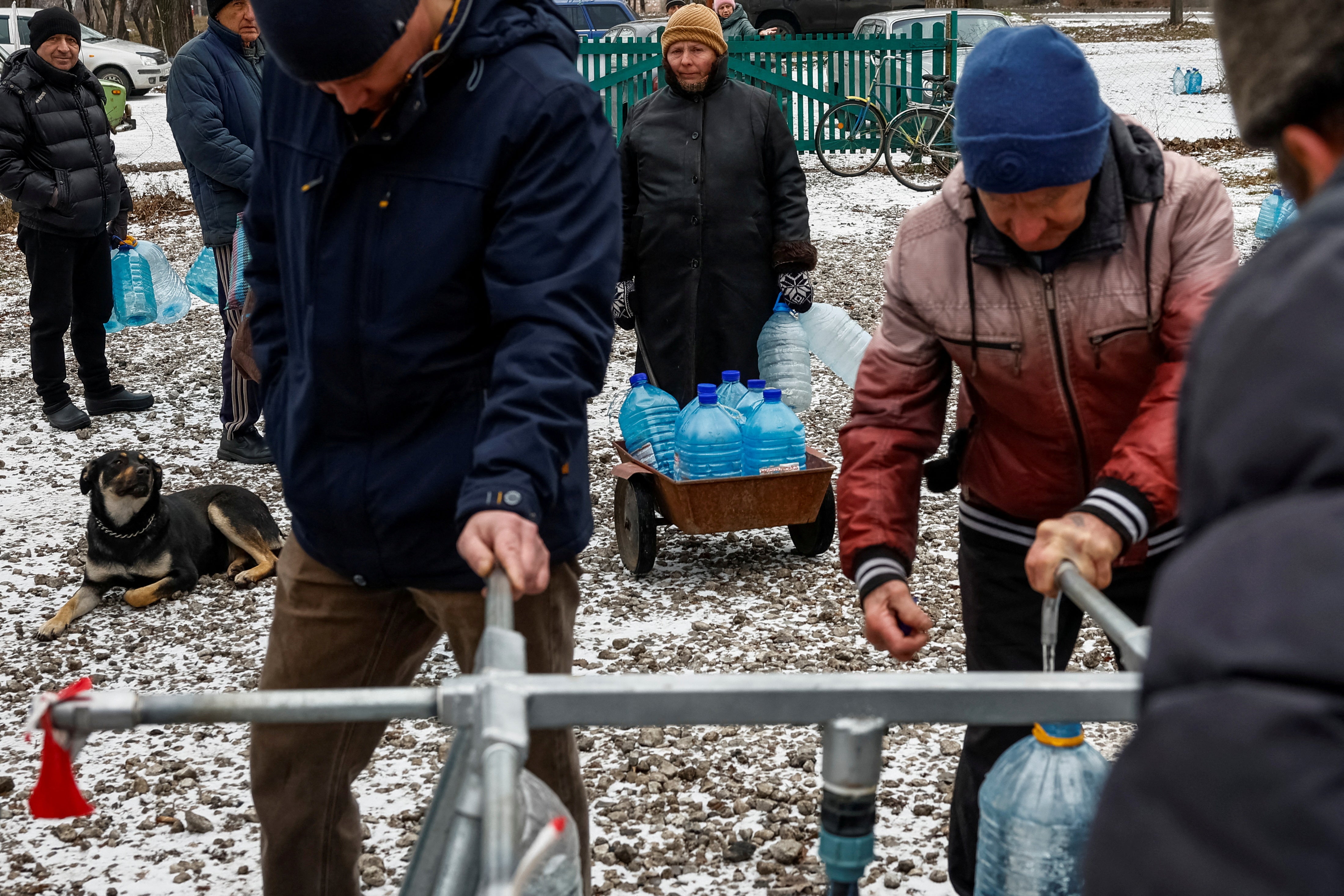 Local residents who refuse to be evacuated, fill plastic bottles with water at a distribution point, while the town struggles with no water supply