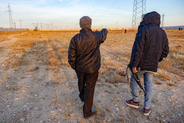 <p>Ahmed (not his real name), a grave digger, points to where he was forced to dig trenches for a mass grave, next to a local opposition fighter</p>