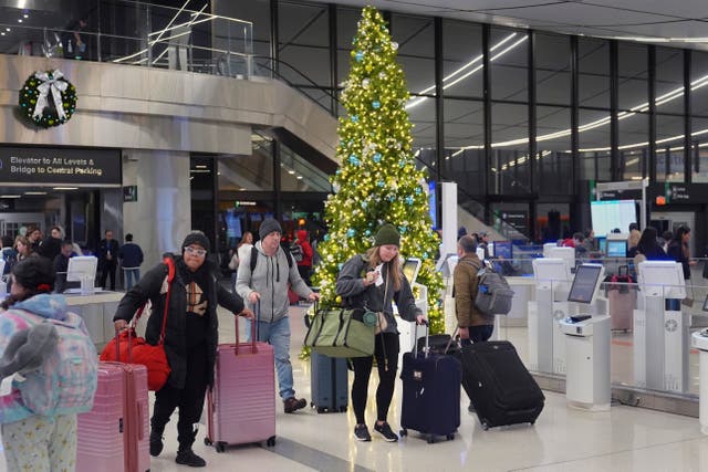 <p>Holiday travelers pass a Christmas tree at Boston’s Logan International Airport on Friday. Nearly 120 million Americans are expected to travel for the holidays this month </p>