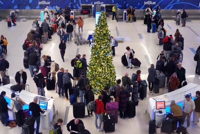 <p>Holiday travelers wait in line to check their bags on Friday at Boston’s Logan International Airport. More than 6,100 delays have been reported at airports around the country </p>