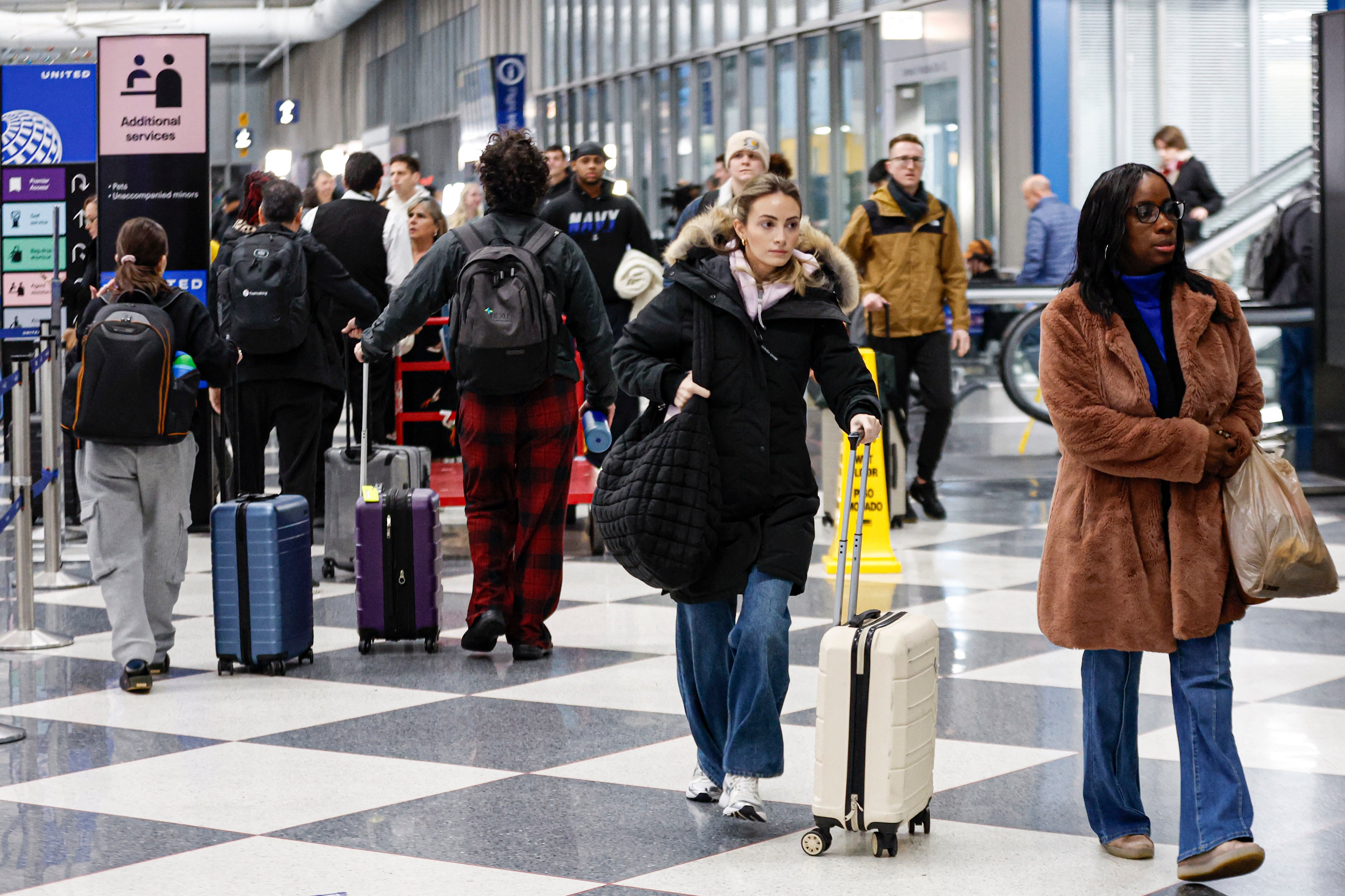 Travelers walk through Chicago’s O’Hare International Airport on Friday. Delays at the hub were linked to snow