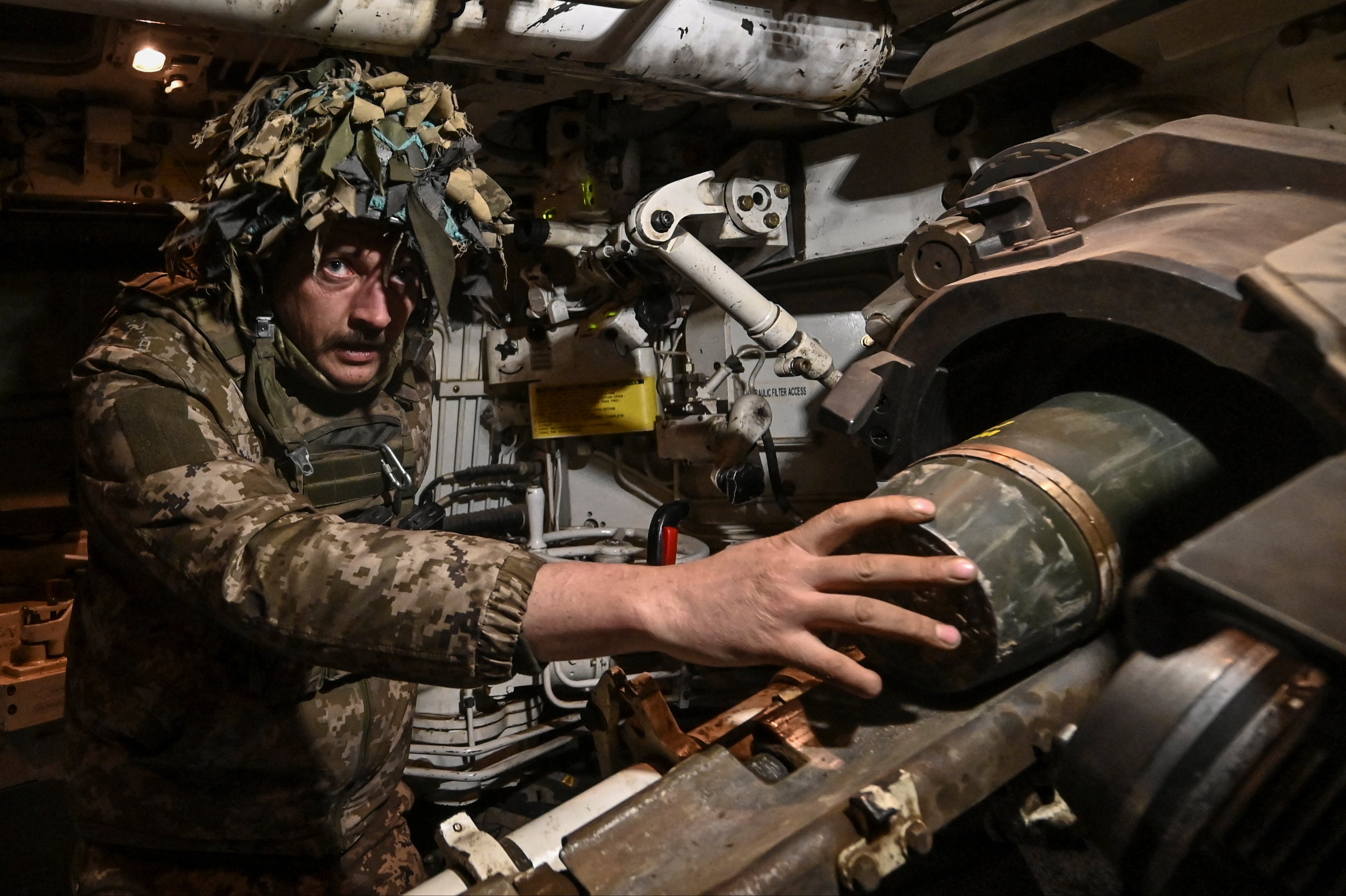 A Ukrainian serviceman of the 118th Separate Mechanized Brigade loads a shell into a barrel of a Paladin M109 self-propelled howitzer before firing towards Russian troops