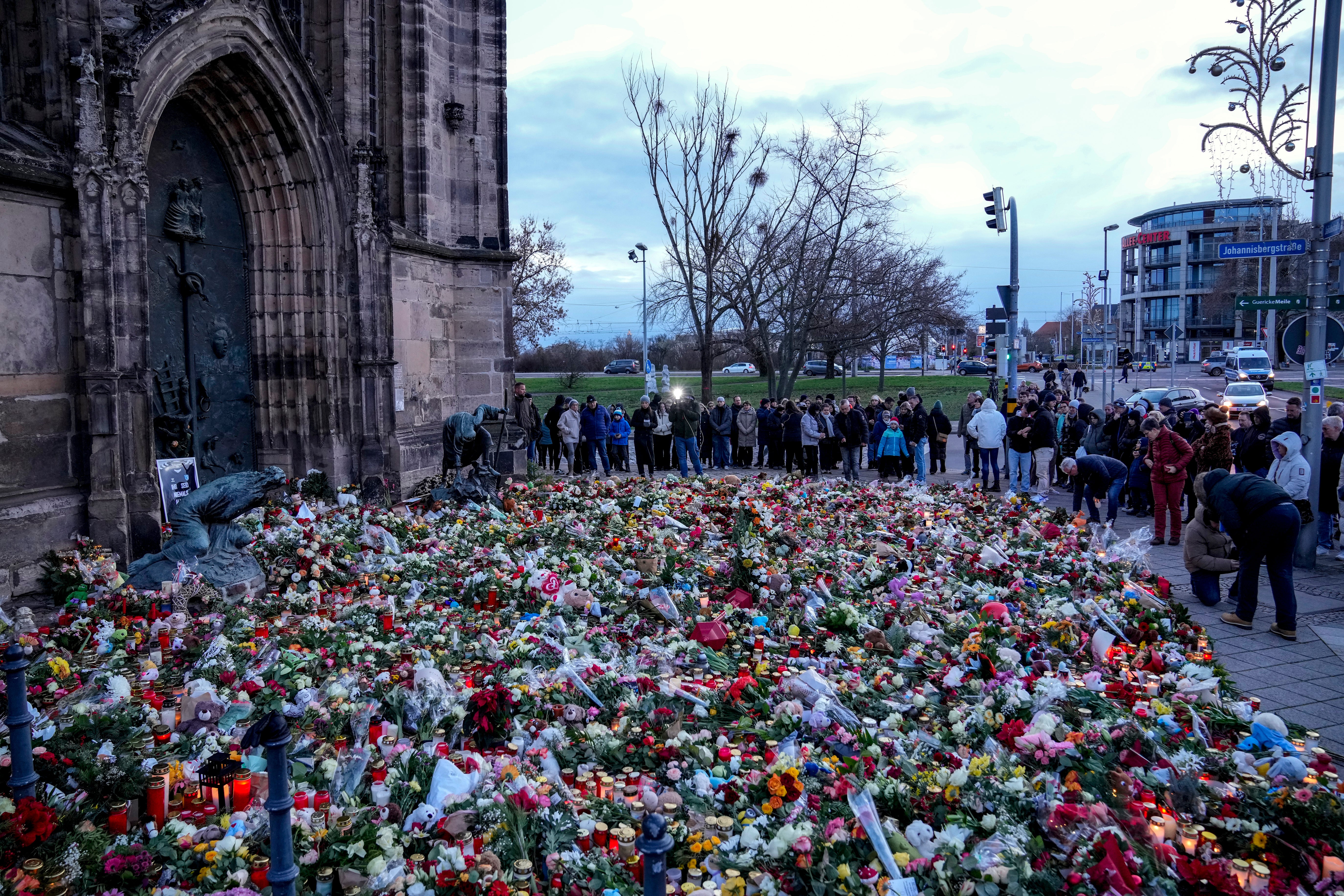 People lay flowers and lit candles in front of the Johannis church close to the Magdeburg Christmas market