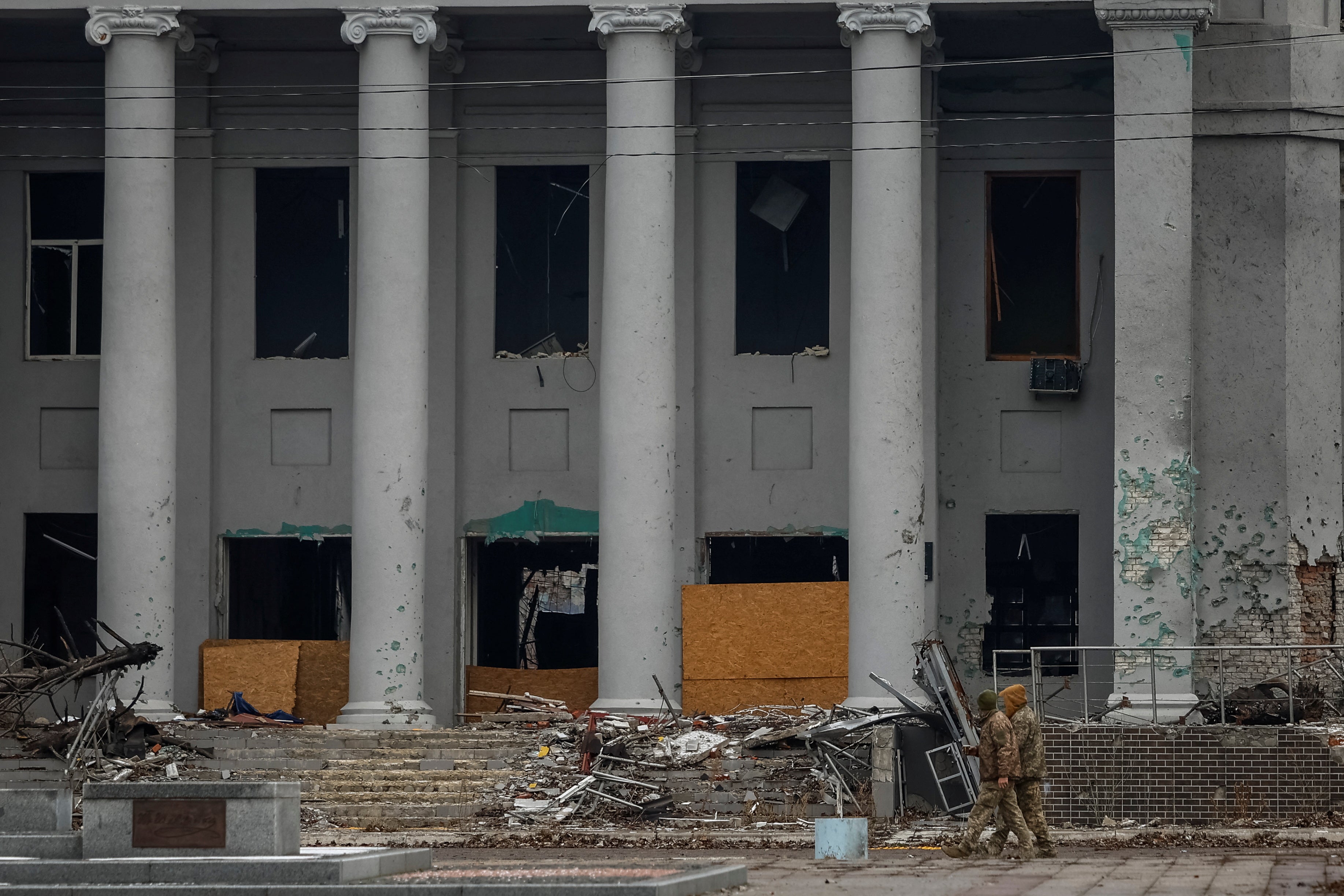 People wearing military clothes walk past a destroyed building of a local university, amid Russia’s attack on Ukraine, in the town of Pokrovsk, near a front line in Donetsk region, Ukraine 19 December 2024