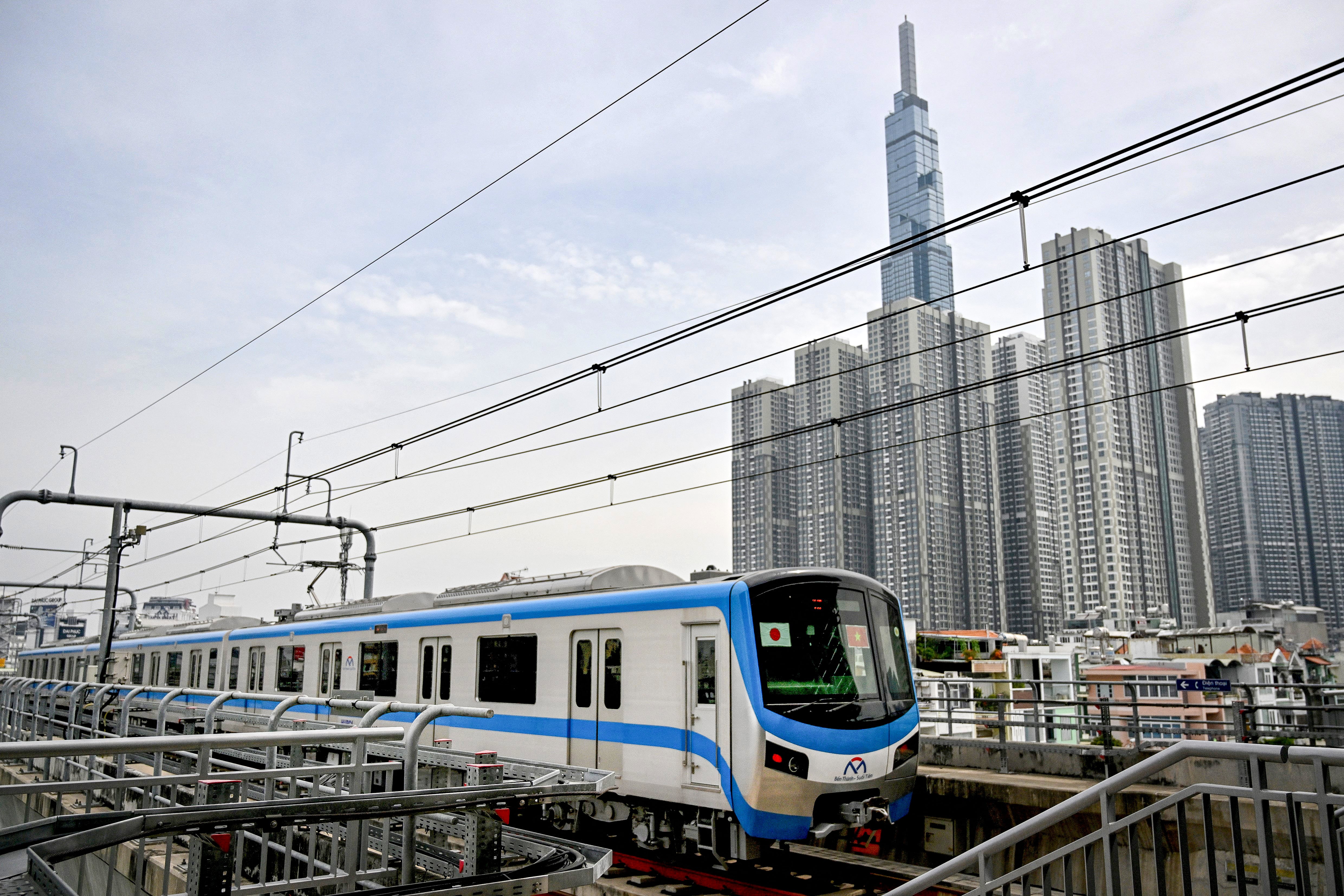 A train of the Line 1 of the HCMC Metro is seen past residential buildings in Ho Chi Minh City on 22 December 2024. Thousands of selfie-taking Ho Chi Minh City residents crammed into train carriages on 22 December, as the traffic-clogged business hub celebrated the opening of its first-ever metro line after years of delays