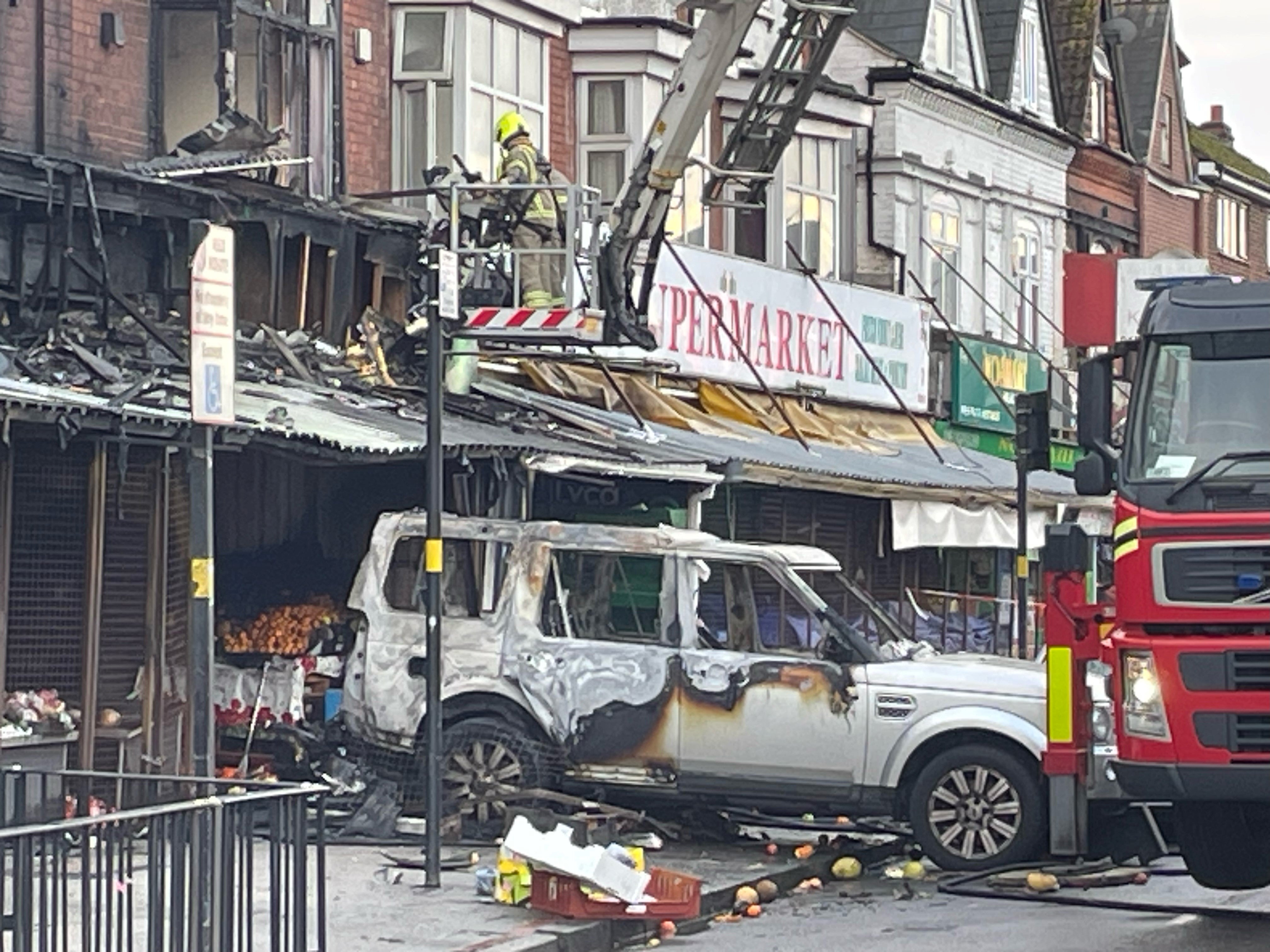 The remains of a burnt out car at the scene of a fire at a mixed commercial and residential premises on Stratford Road