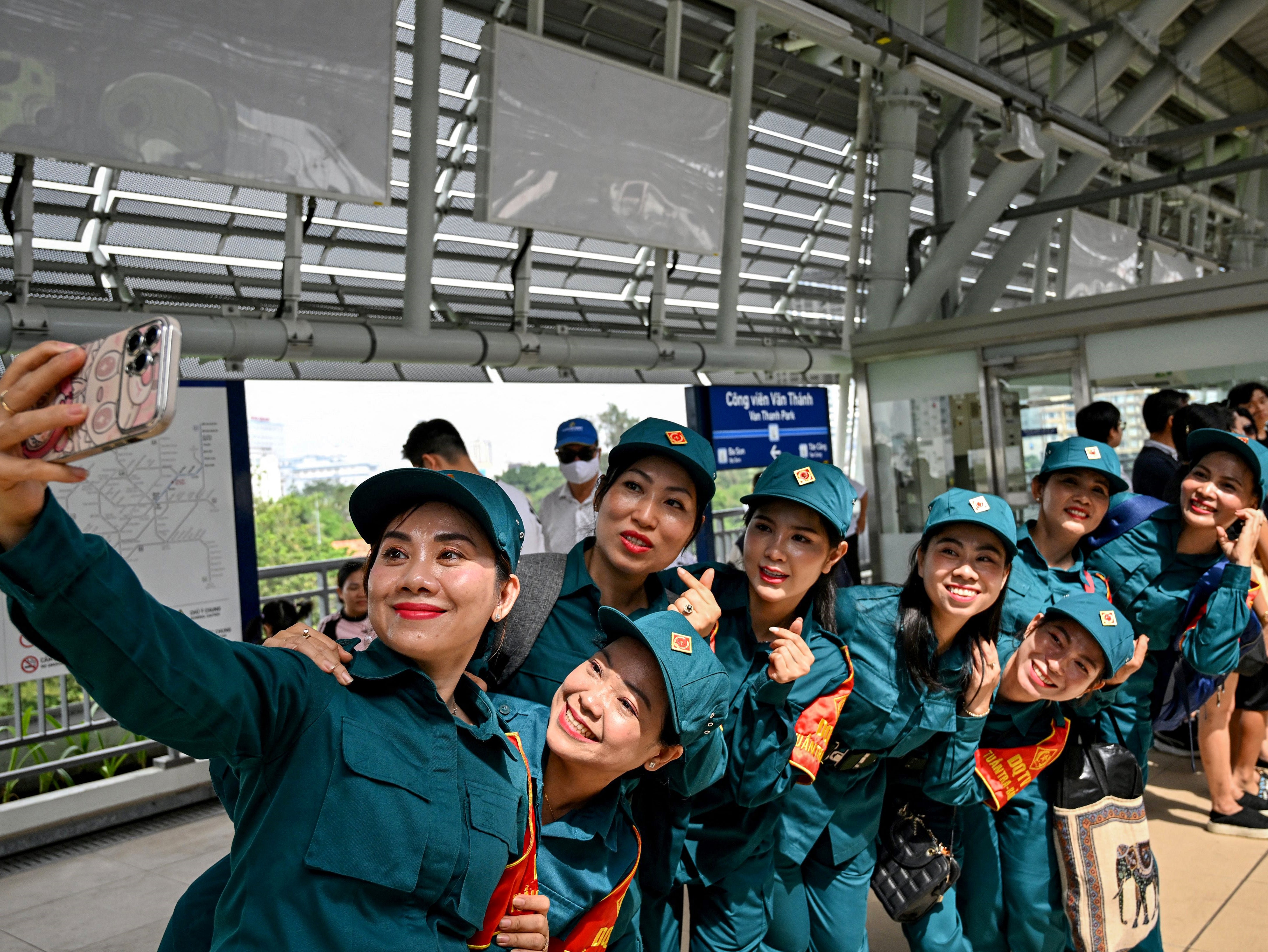 Soldiers take a selfie on the plateform at a metro station in Ho Chi Minh City on 22 December 2024. Thousands of selfie-taking Ho Chi Minh City residents crammed into train carriages on 22 December as the traffic-clogged business hub celebrated the opening of its first-ever metro line after years of delays