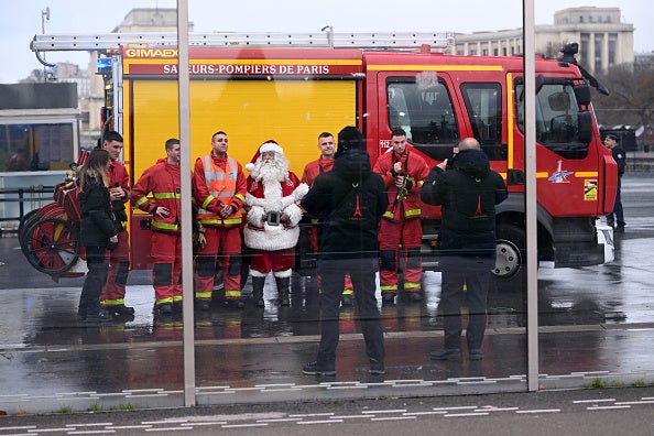 Firefighters pose for a picture with a Santa Claus near the Eiffel Tower as the site was closed and then reopened after a fire alarm, on December 24, 2024