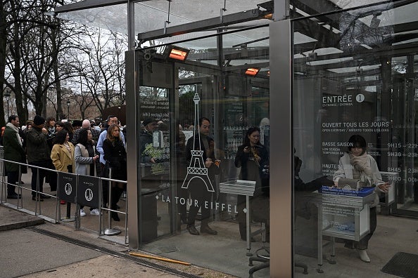 Visitors wait in line to visit the Eiffel Tower as the site was closed and then reopened after a fire alarm