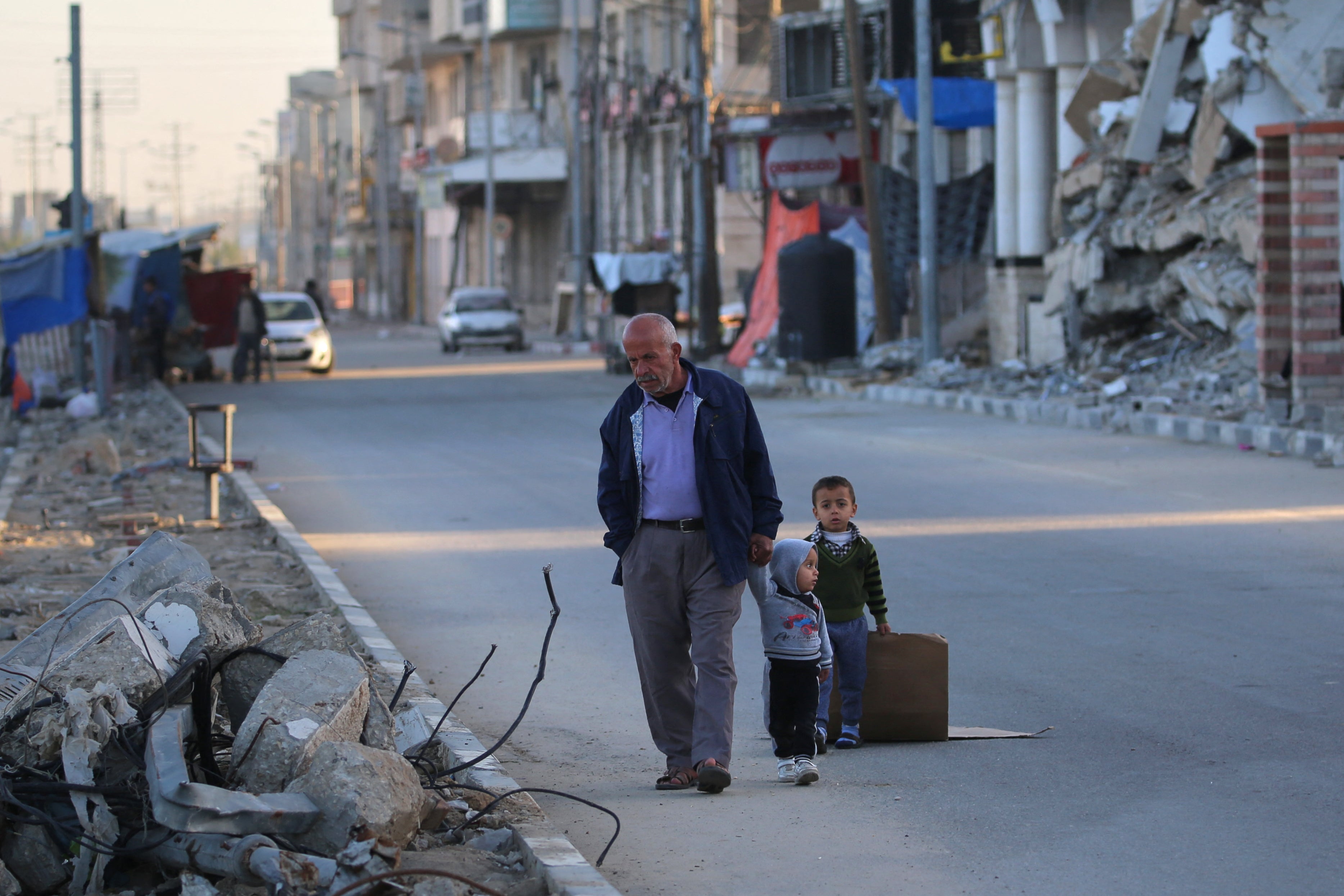 A Palestinian man walks with children in Deir el-Balah in the central Gaza Strip on 24 December