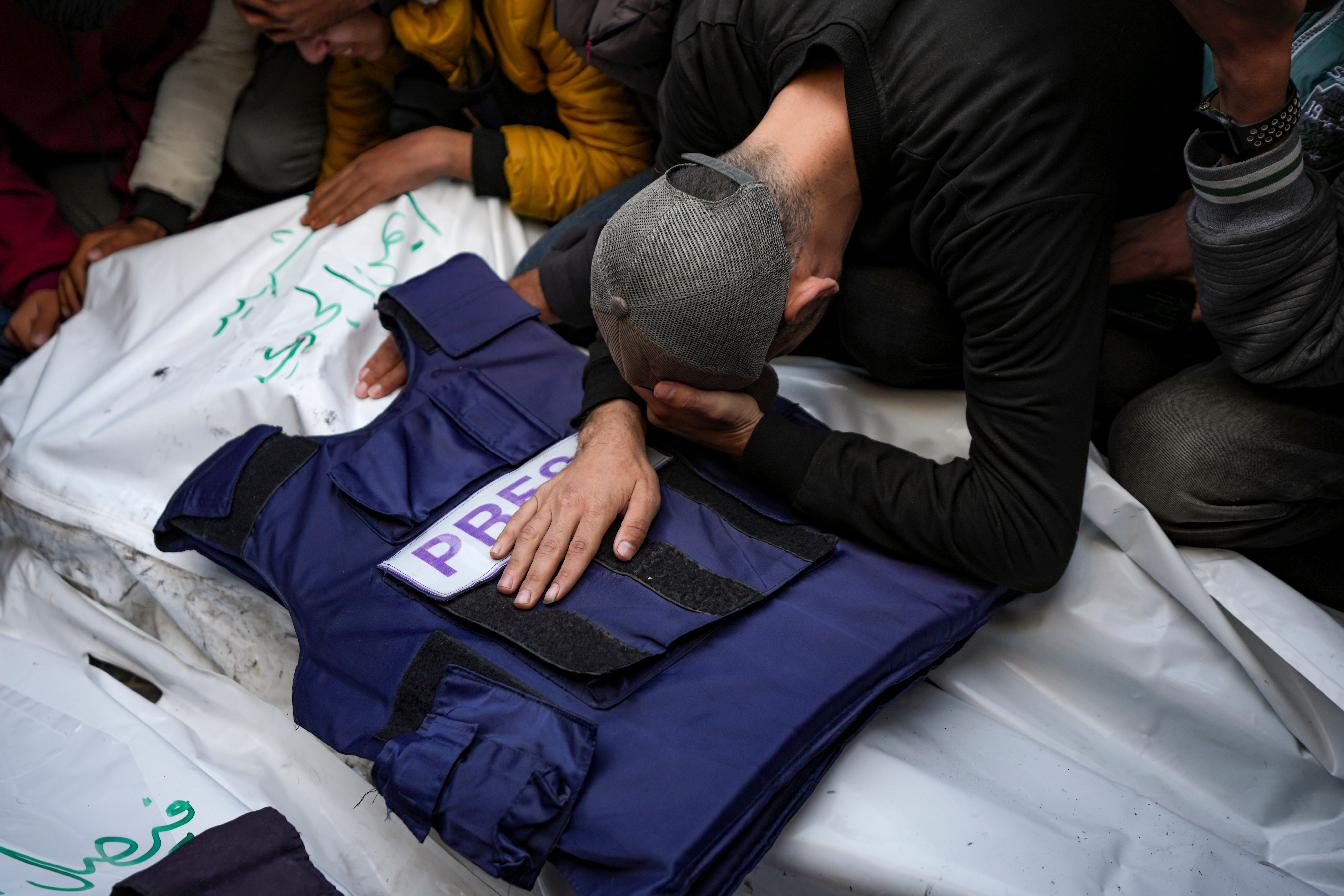 A relative mourns over the body of one of the five Palestinian journalists killed by Israel in December 2024