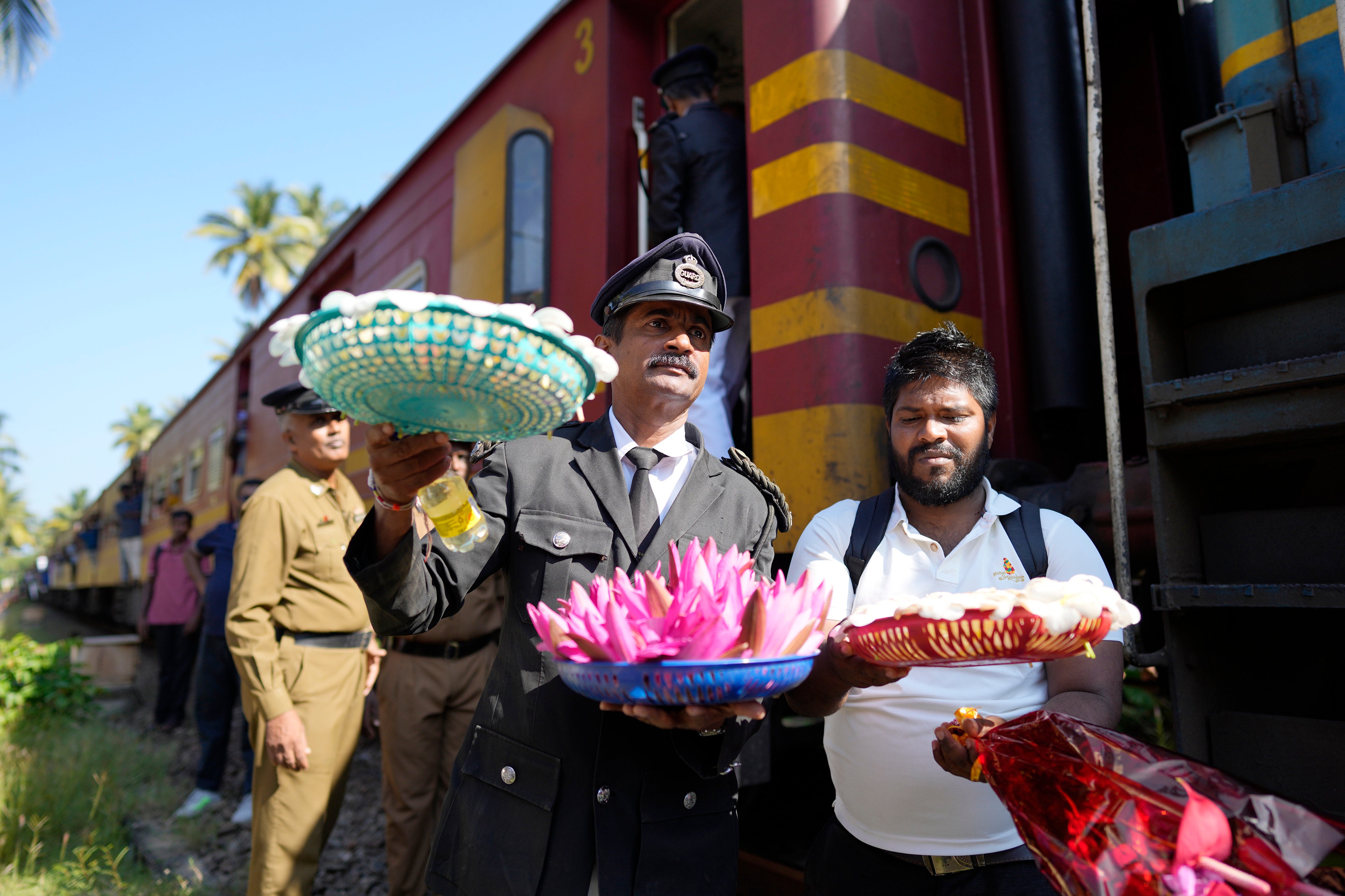 Railway workers carried flowers to offer a monument built in memory of those killed during the 2004 Indian Ocean tsunami in Sri Lanka