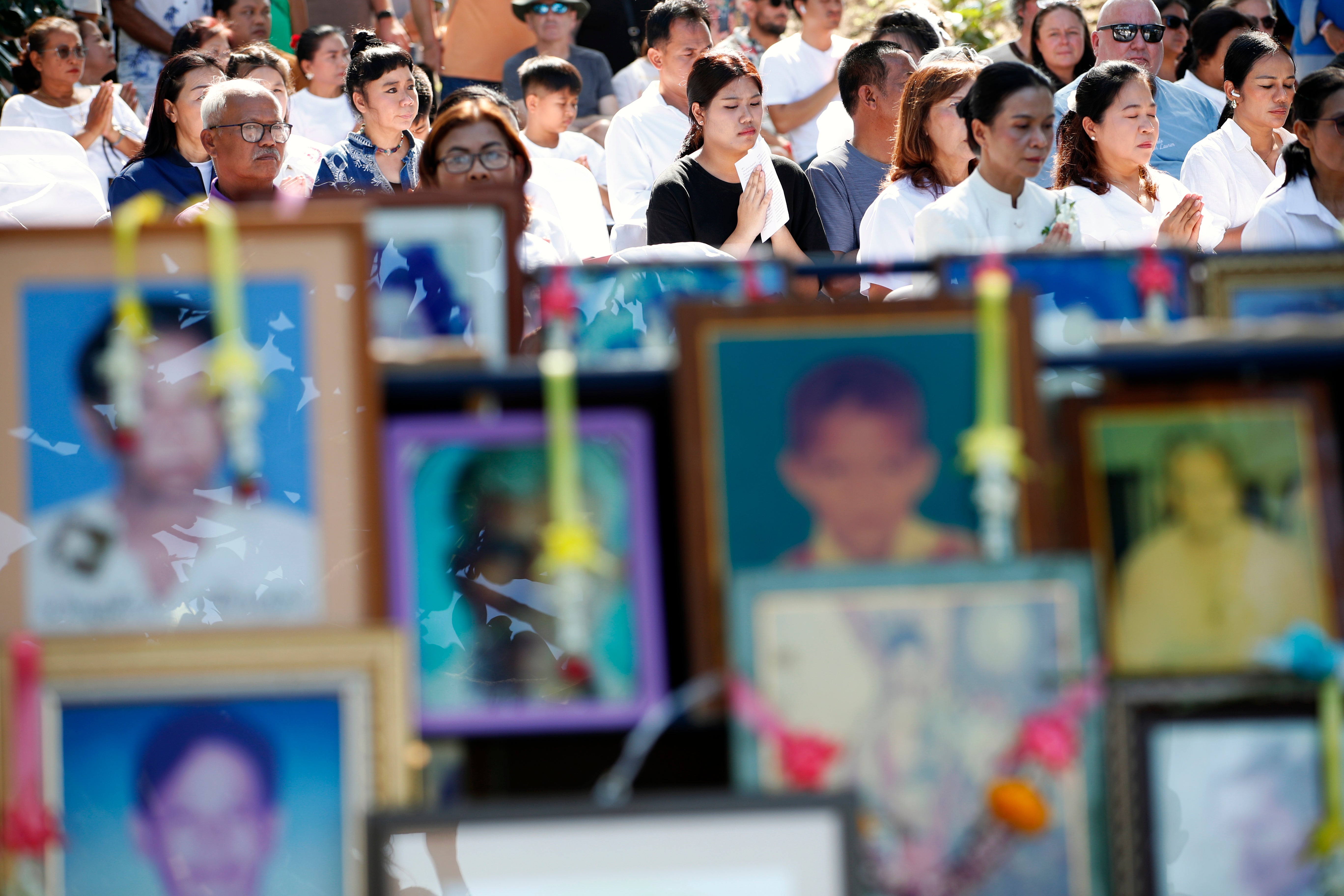 Family members chant next to photographs of tsunami victims in Thailand