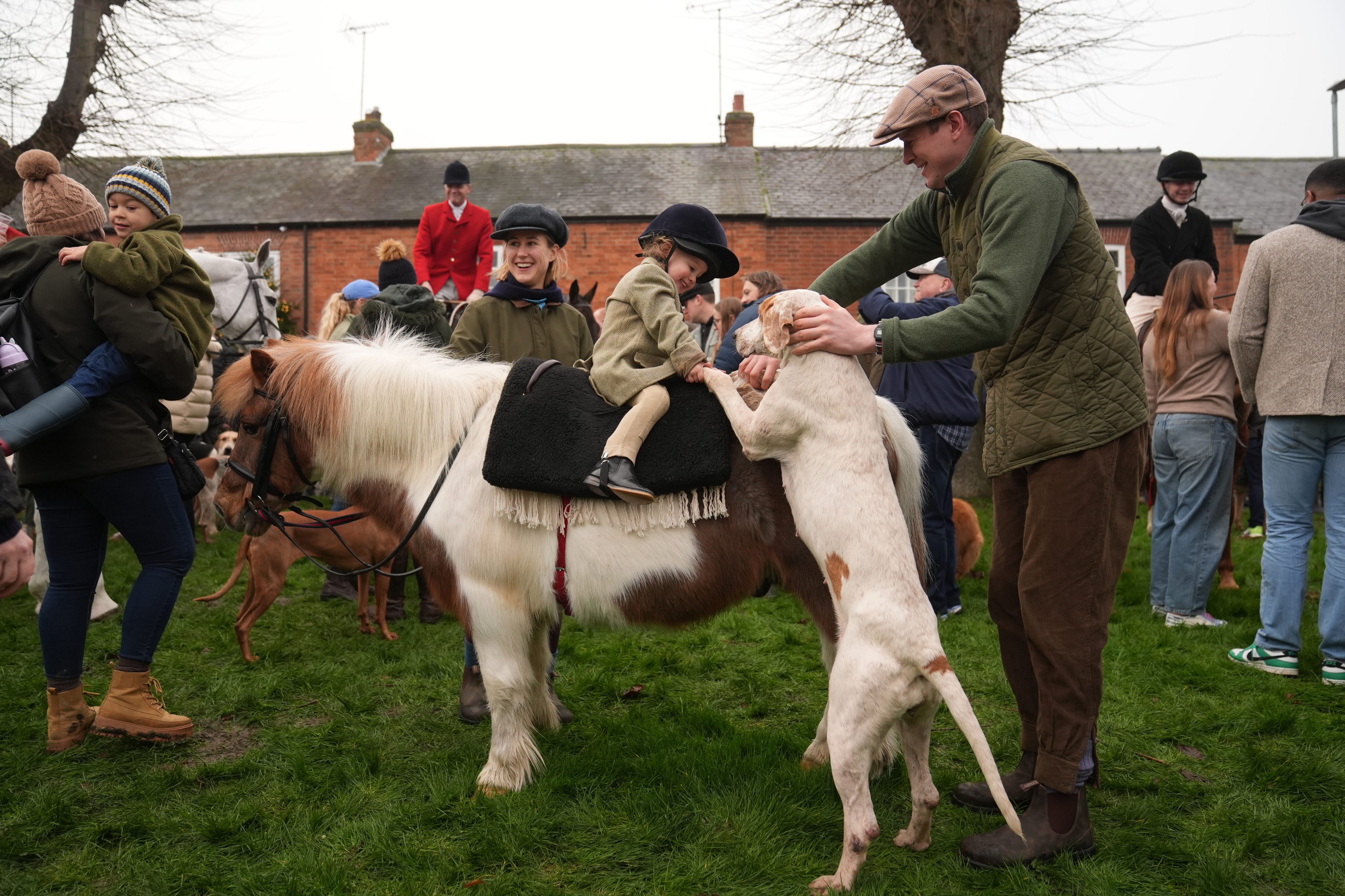 Two-year-old Clementine Soames with pony Horlicks and one of the hounds as riders gather for the annual Fernie Hunt Boxing Day meet in Leicestershire (Joe Giddens/PA)