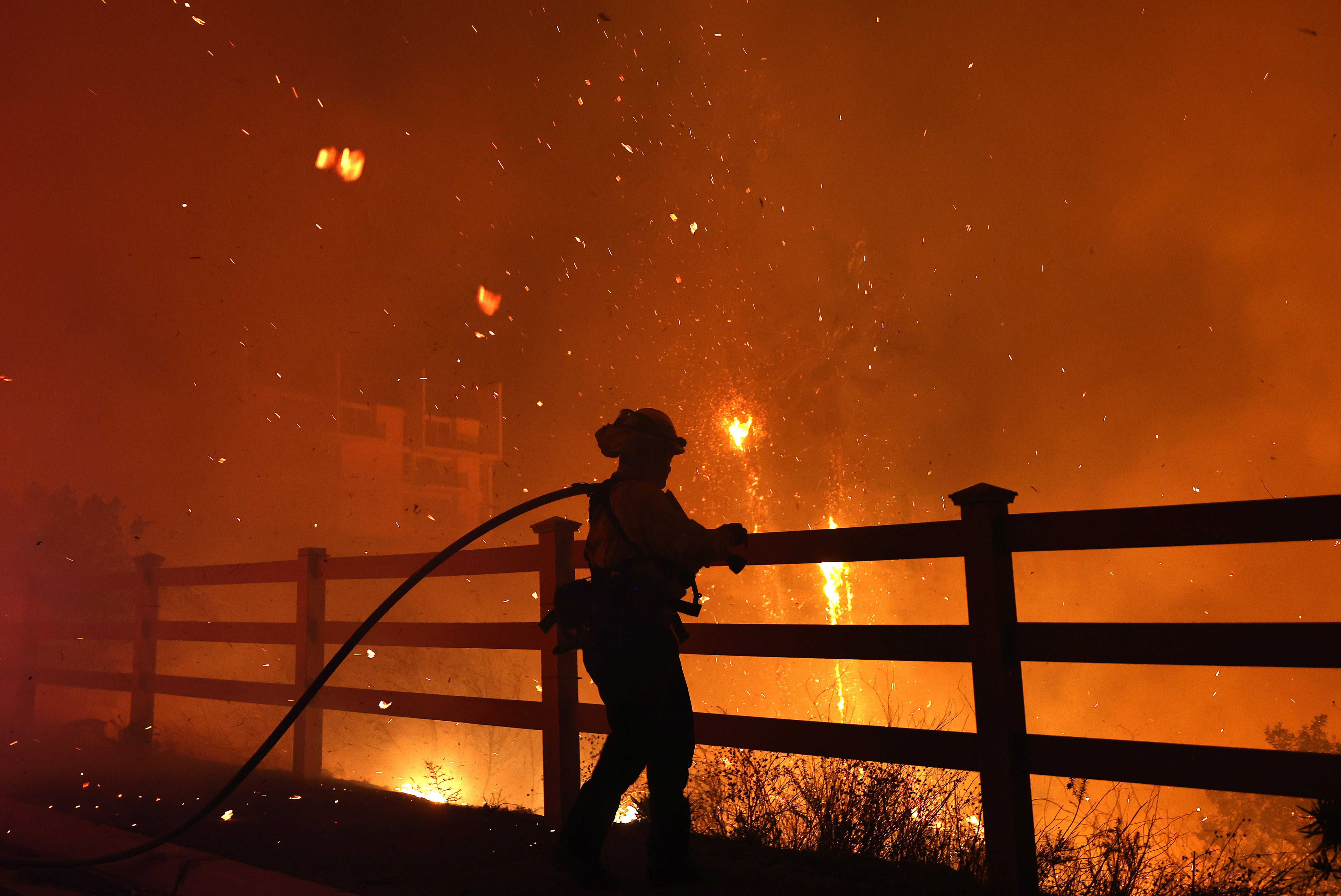 A firefighter with a hose stands near a burning building during December’s Franklin Fire in Malibu, California. The late-year wildfire forced evacuations for thousands and destroyed several homes. Now, a new estimate says extreme weather events this year will cost the country more than $500 billion in total damage and loss