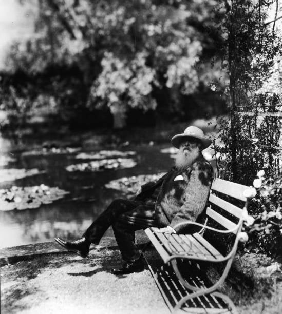 Claude Monet ao lado do lago com nenúfares no jardim de sua casa em Giverny